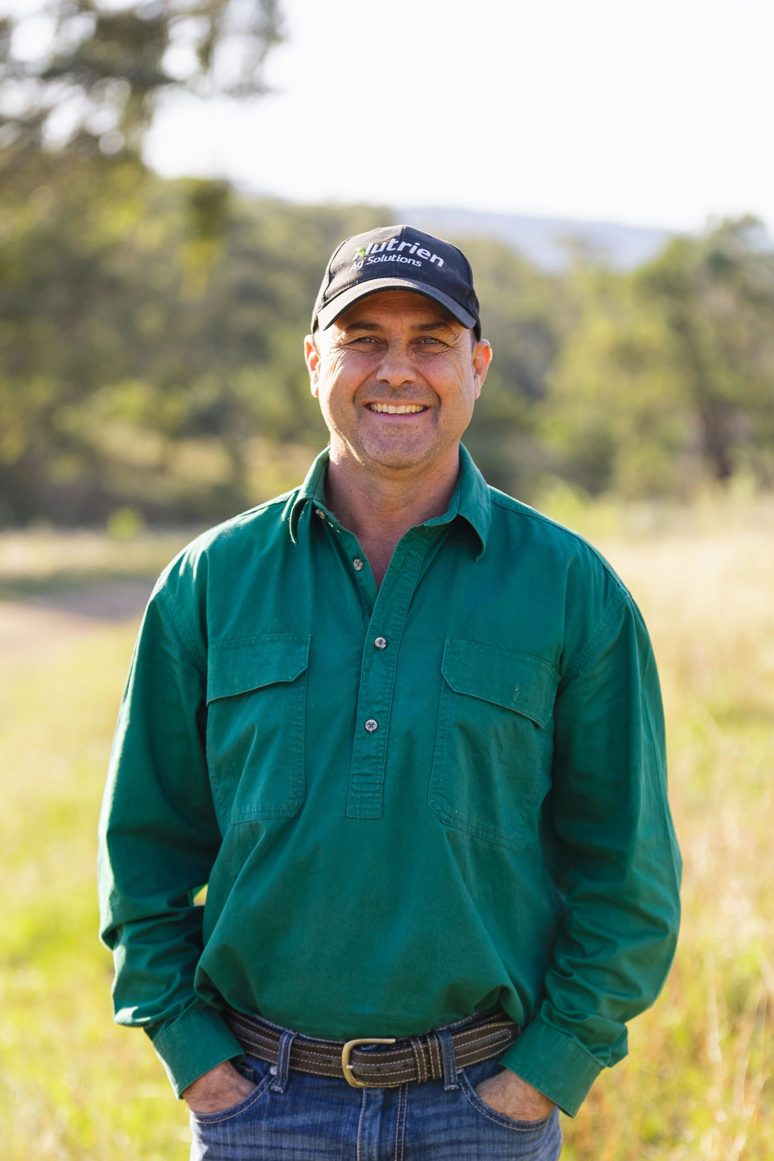 Man standing with hands in pockets with Nutrien Ag Solutions hat on