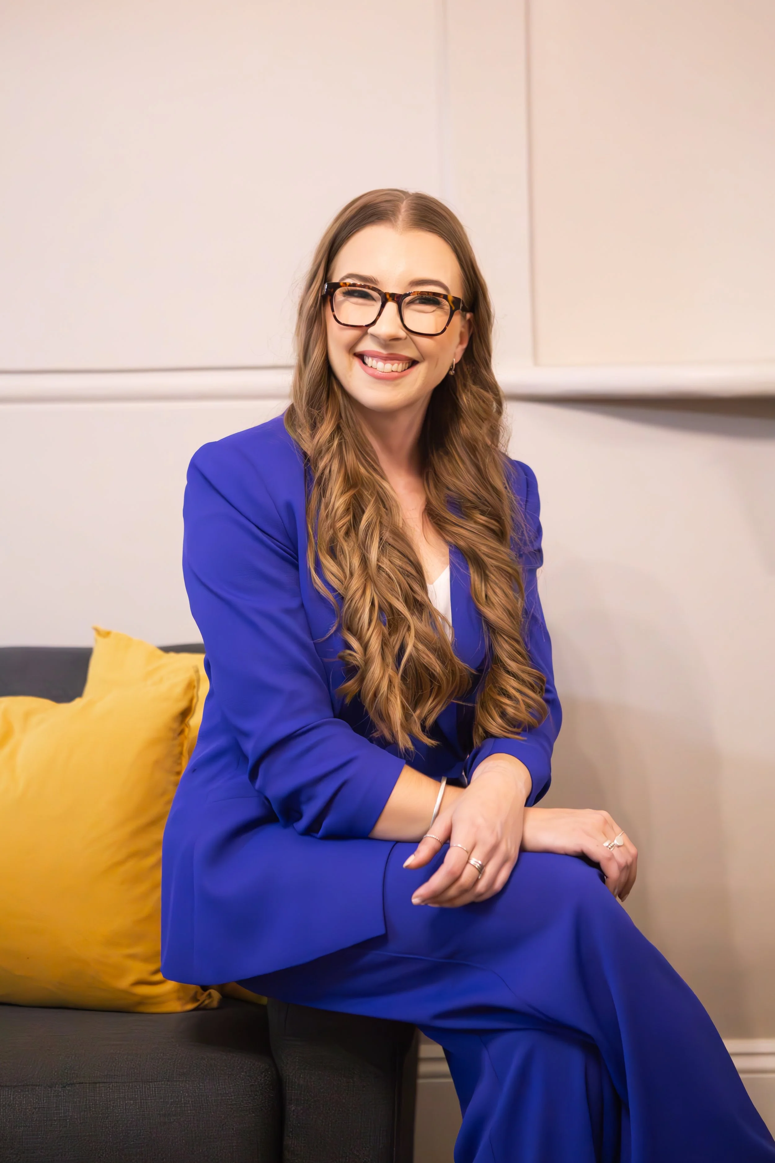woman in blue suit sitting on lounge smiling