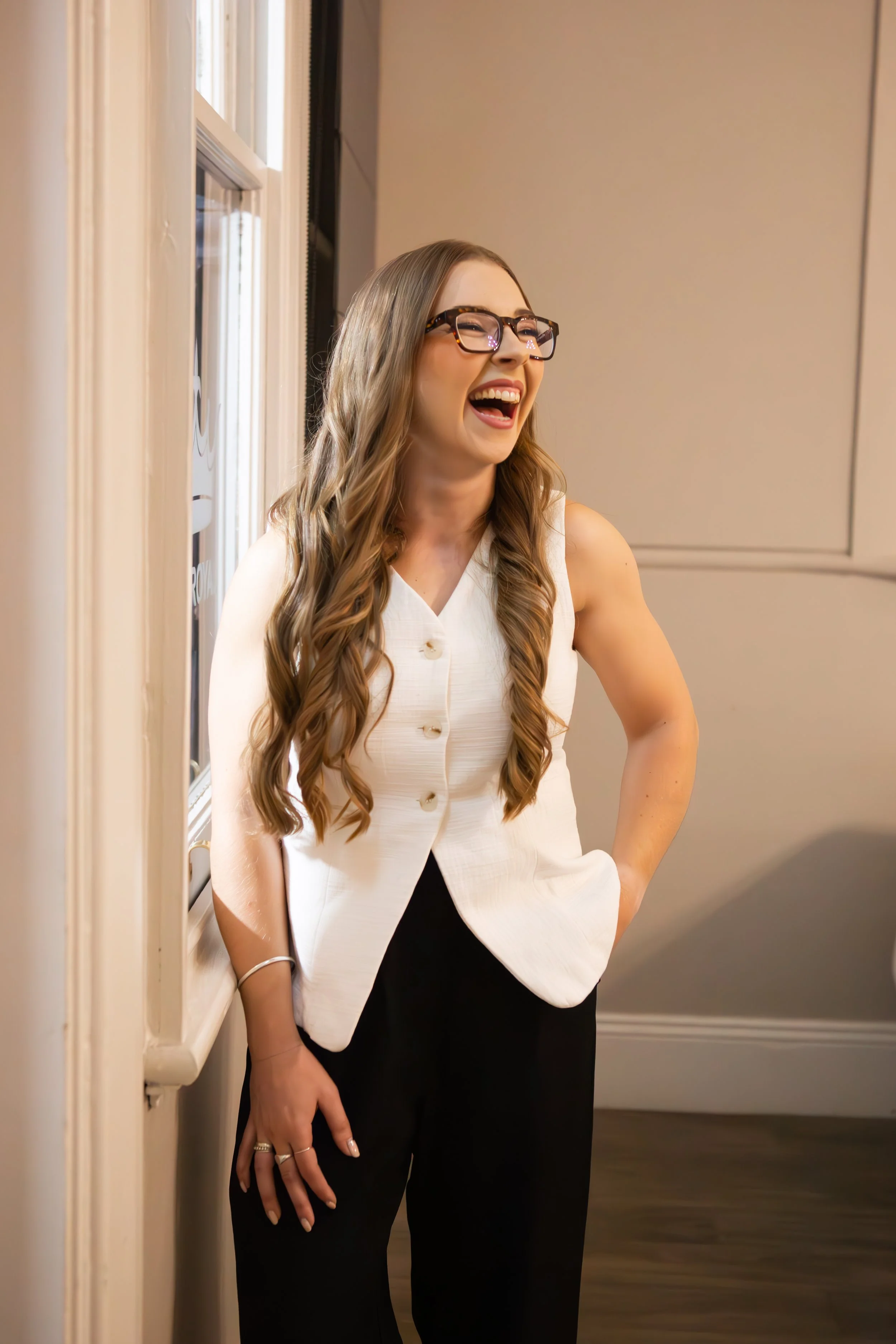 woman laughing standing next to window