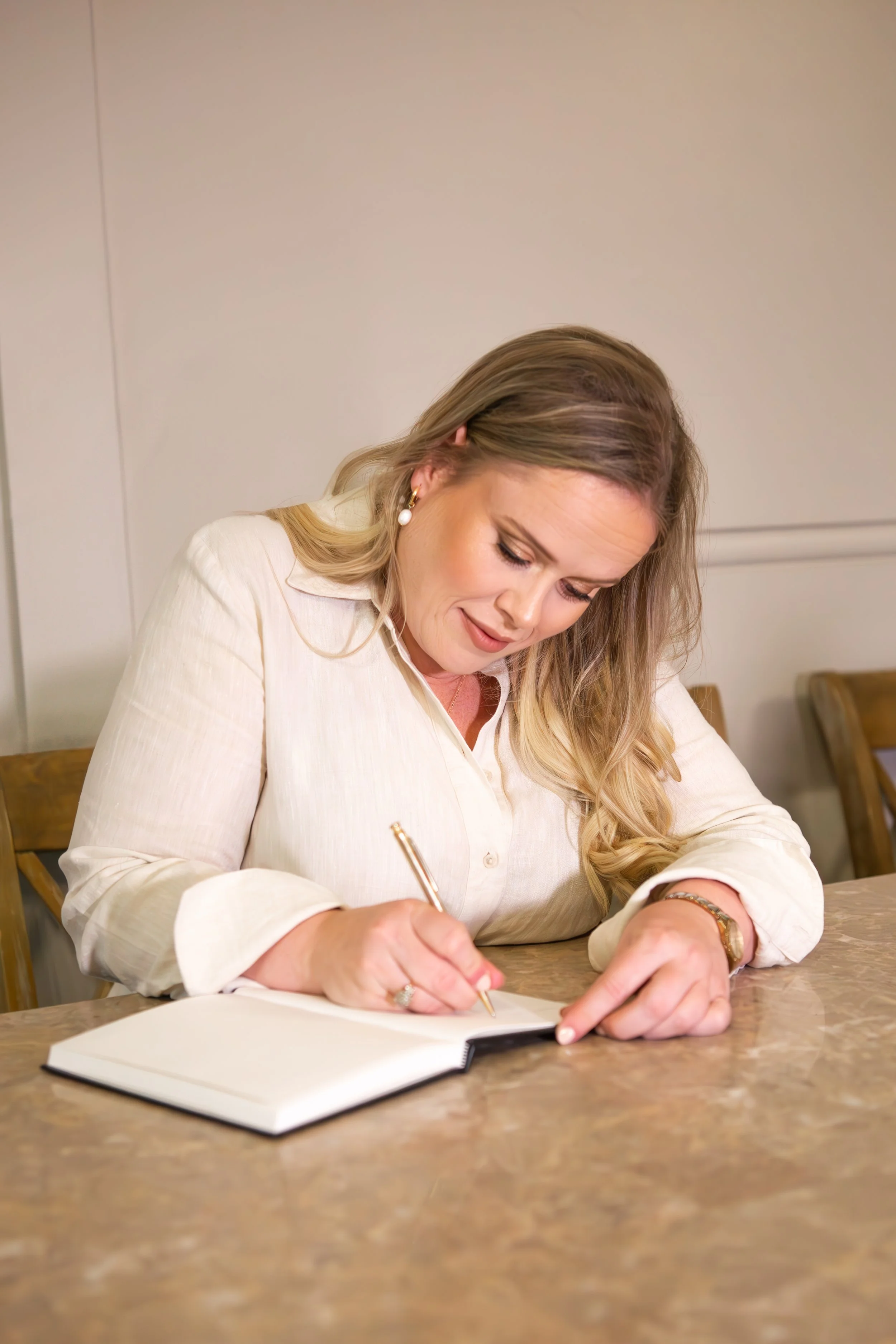 women in cream dress writing in notebook