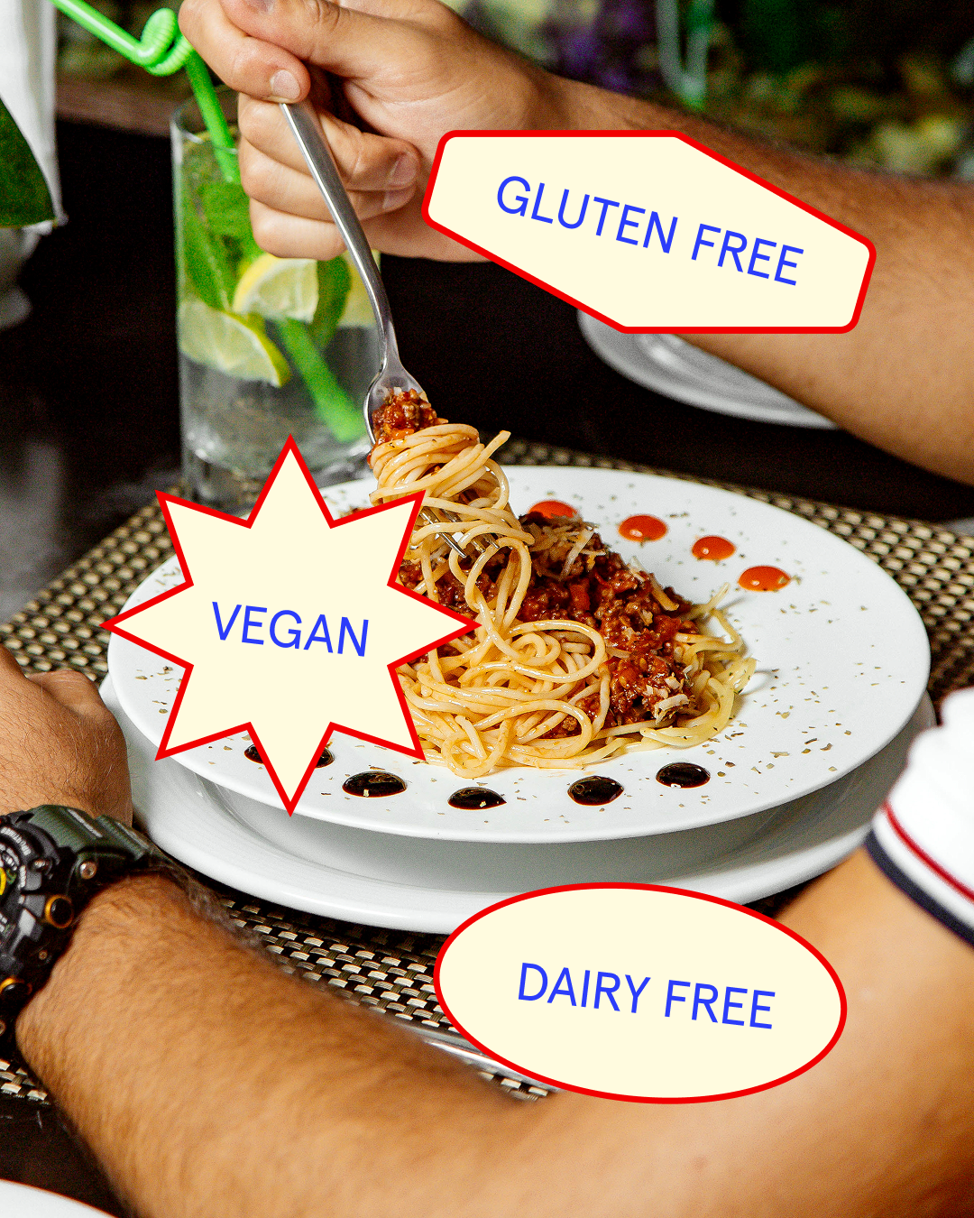 Plate of vegan spaghetti with tomato sauce on a white dish, garnished with sauce drops. A person is twirling spaghetti with a fork, with a glass of water and lemon slices in the background. The image has labels indicating the dish is gluten free, veg