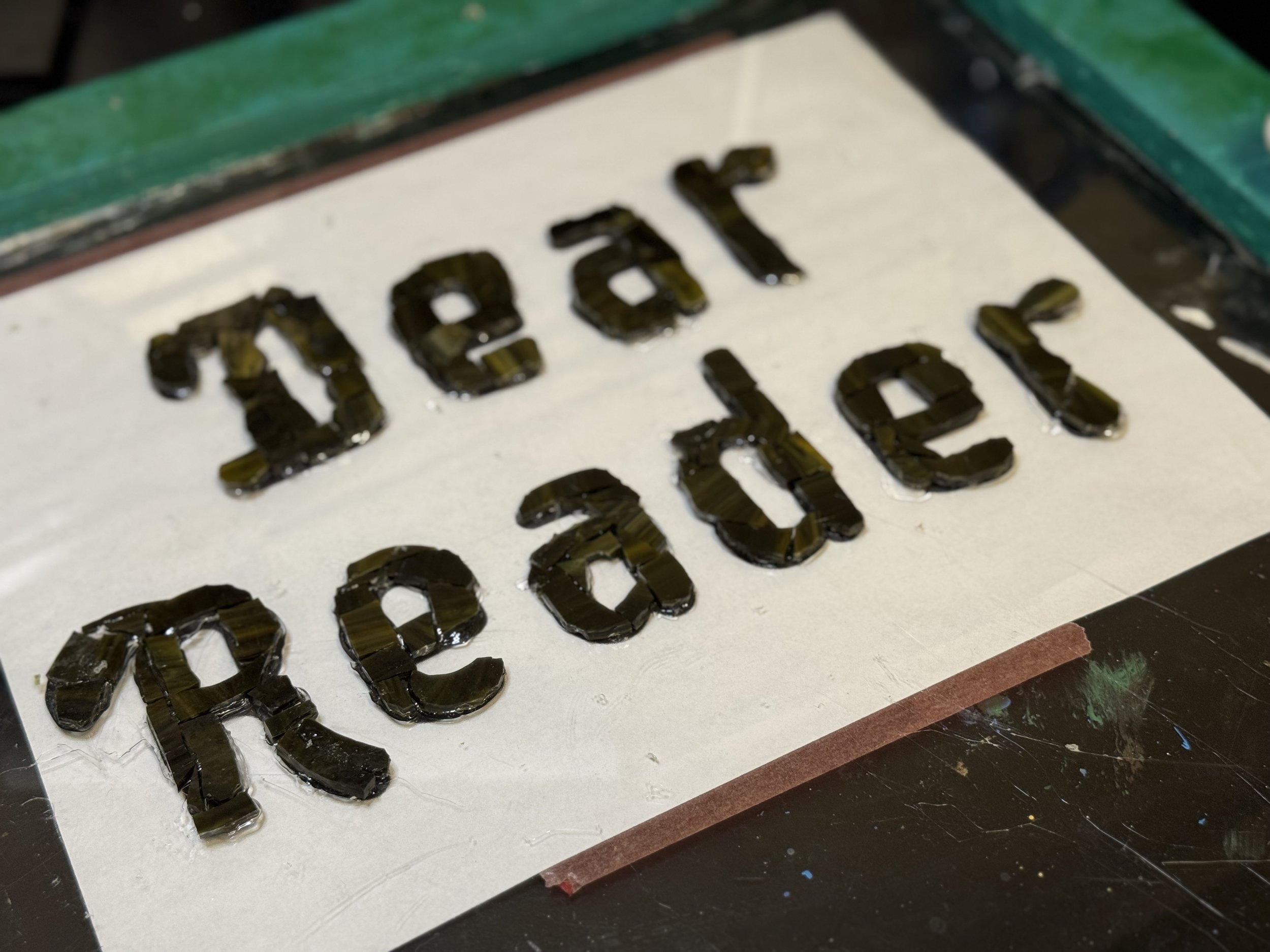 Dear Reader, the glass text, is glued down.