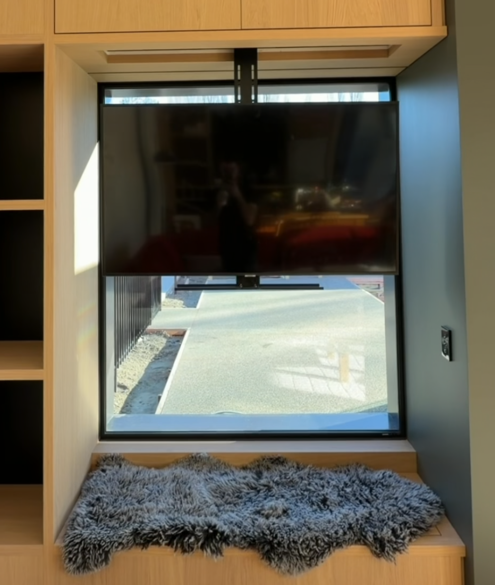 A window seat by day with a tv that drops down at night. Designed by Candela Architecture to allow the clients to have a feature artwork as the focal point of the room.
