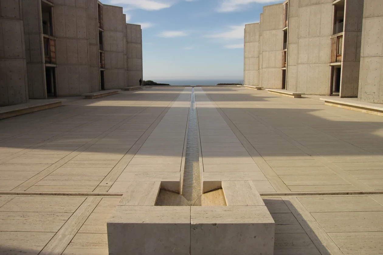 Soft evening light casting long shadows across a concrete courtyard at the Salk Institute