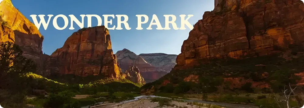 Landscape view of Zion National Park showcasing large red rock formations, a river running through the valley, and clear blue sky with green foliage in the foreground.