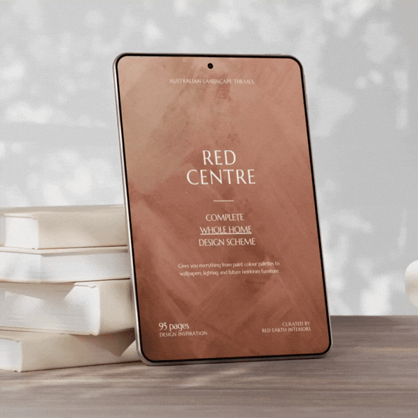 Tablet displaying a book cover titled "Red Centre" with a watercolor background, on a wooden surface next to stacked books.