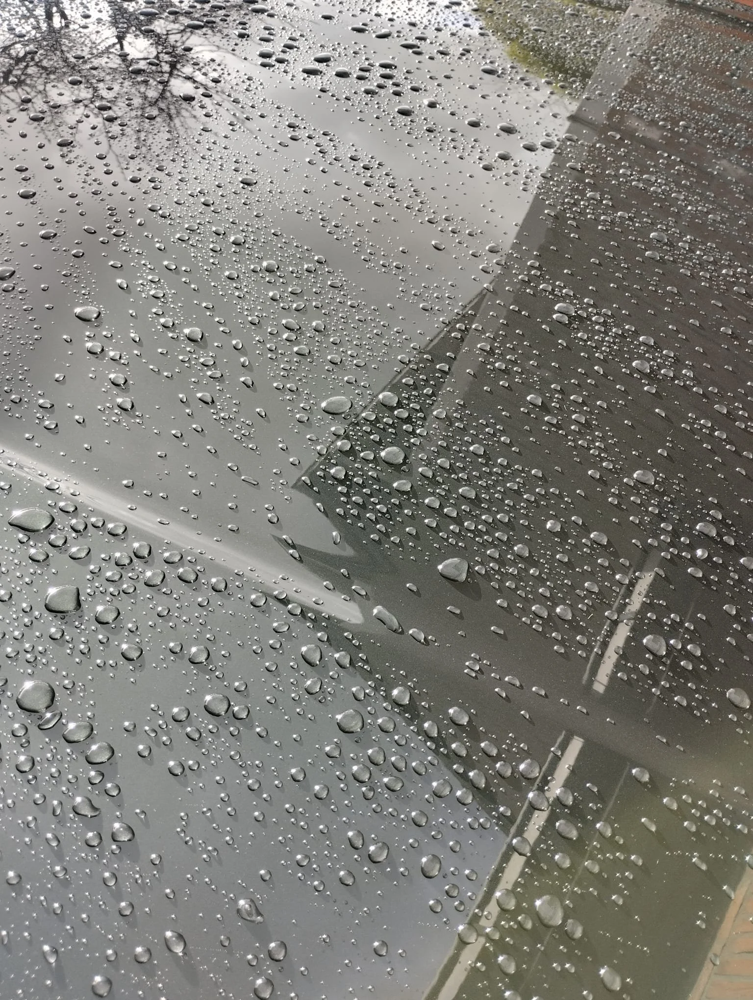 Regenwater druppels op een glad metalen oppervlak.