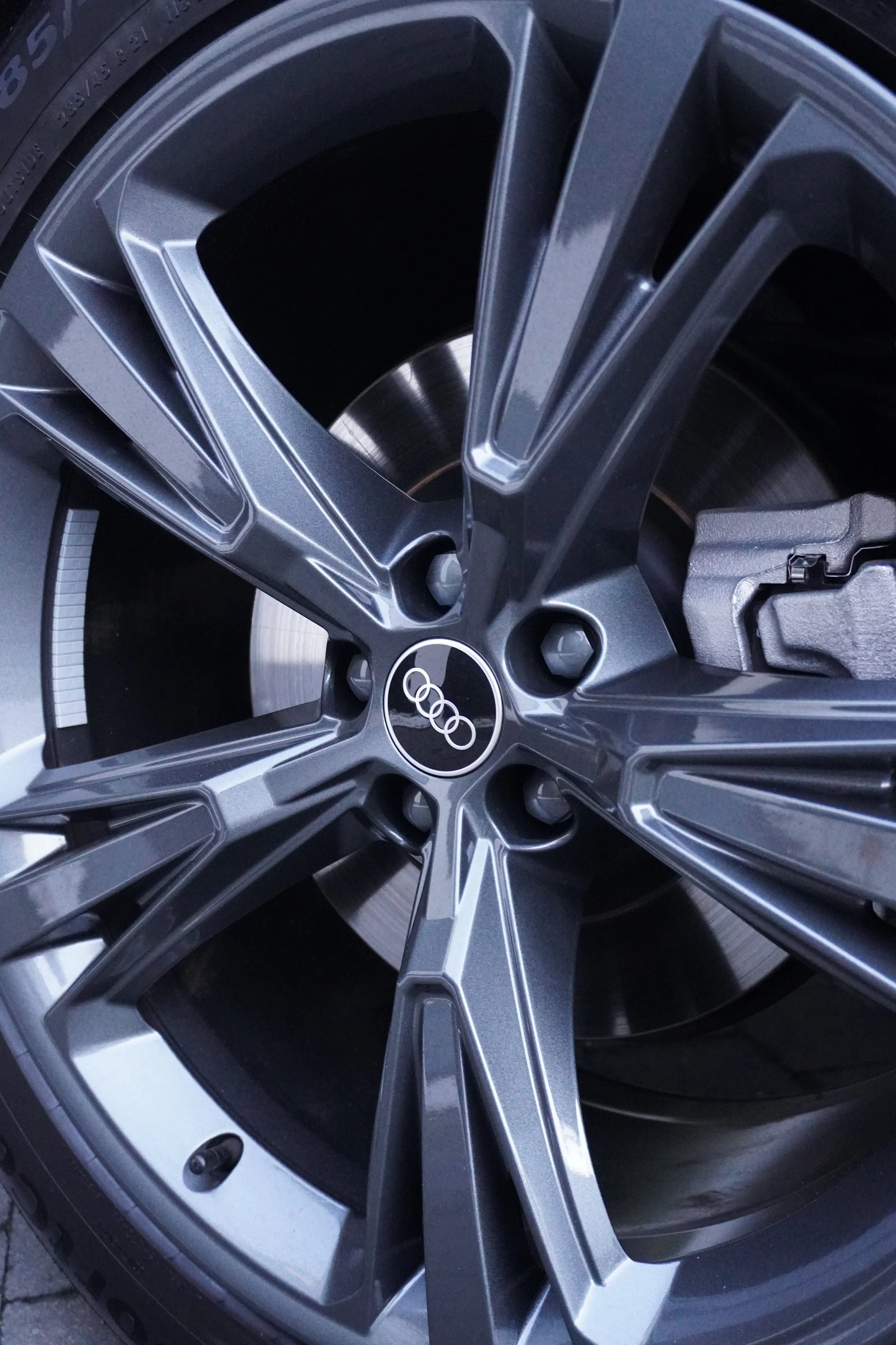 Close-up van een Audi-velg met een zwart en zilverkleurig ontwerp, gemonteerd op een auto.
