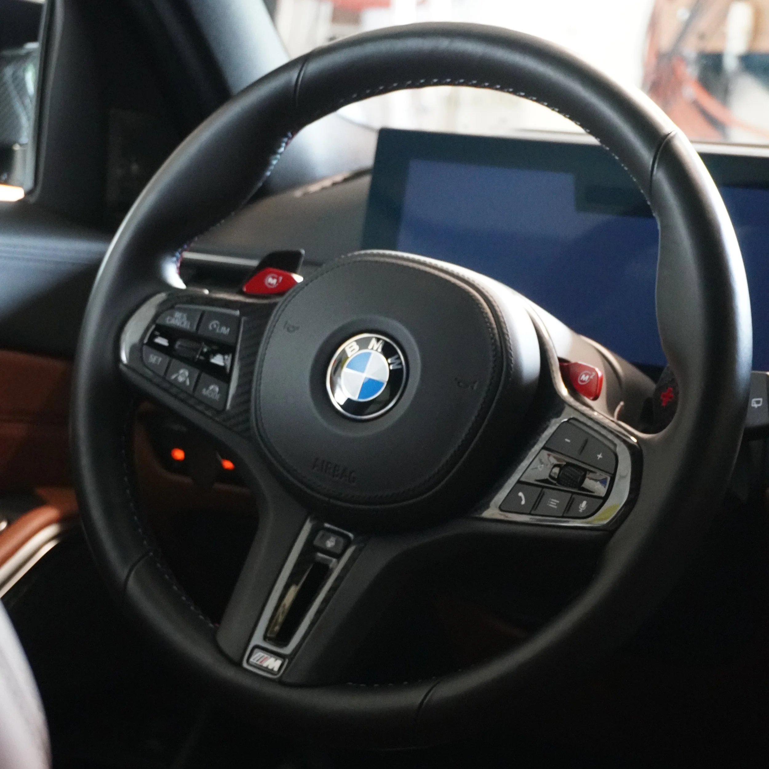 Binnenkant van een BMW auto met stuurwiel en bedieningsknoppen zichtbaar.
