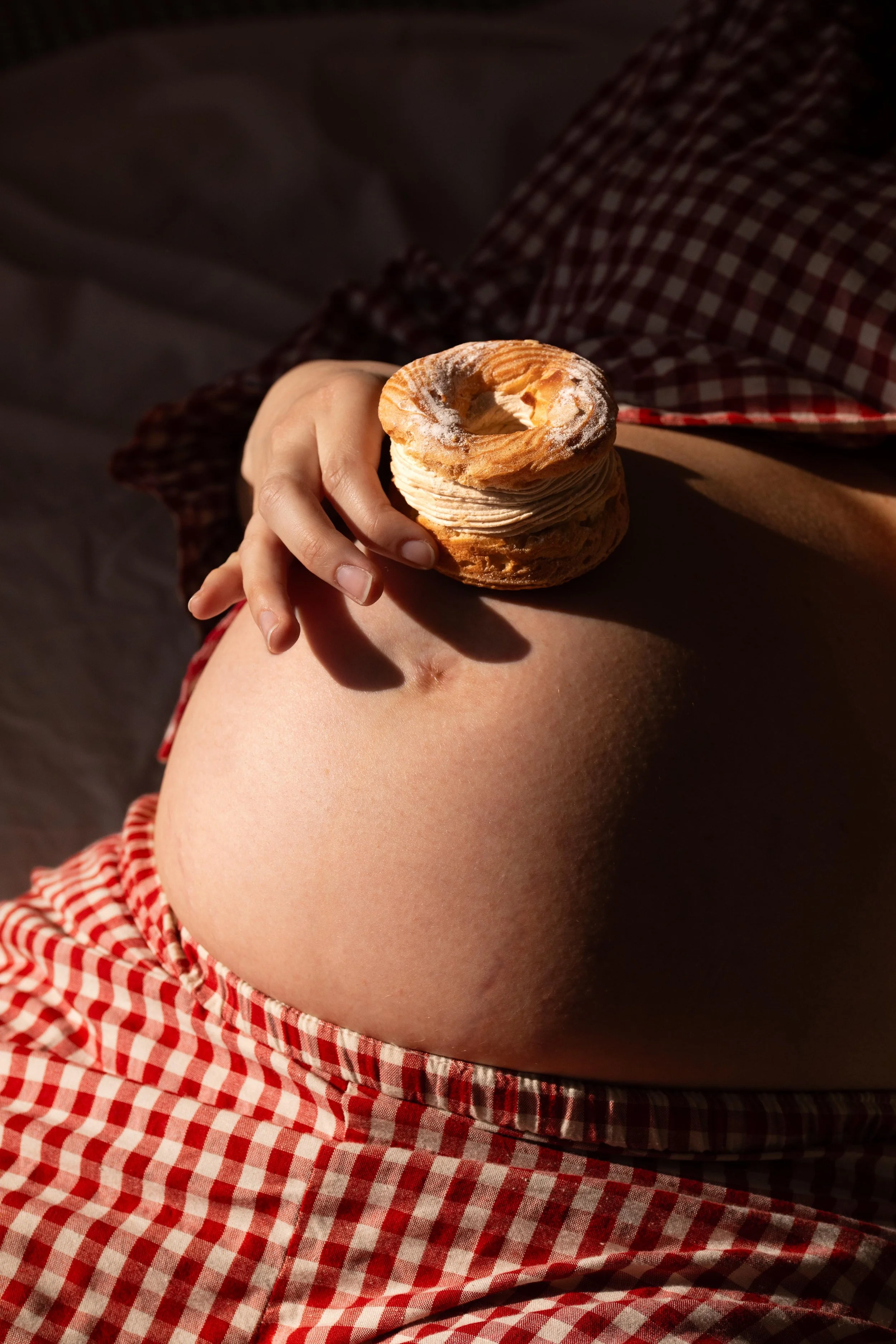 Ventre de femme enceinte avec un Paris-Brest posé dessus