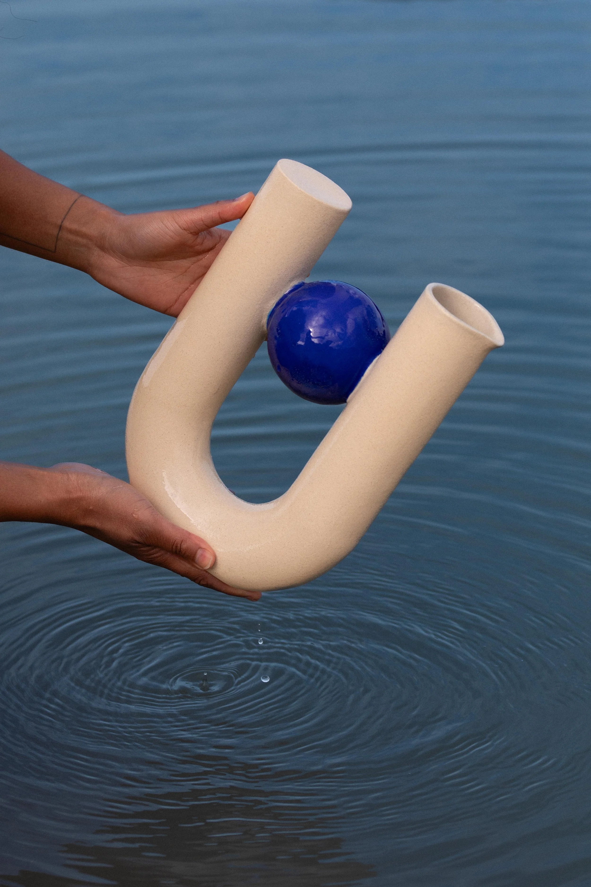 Vase d'Art en céramique porté dans les mains d'une femme au dessus de l'eau