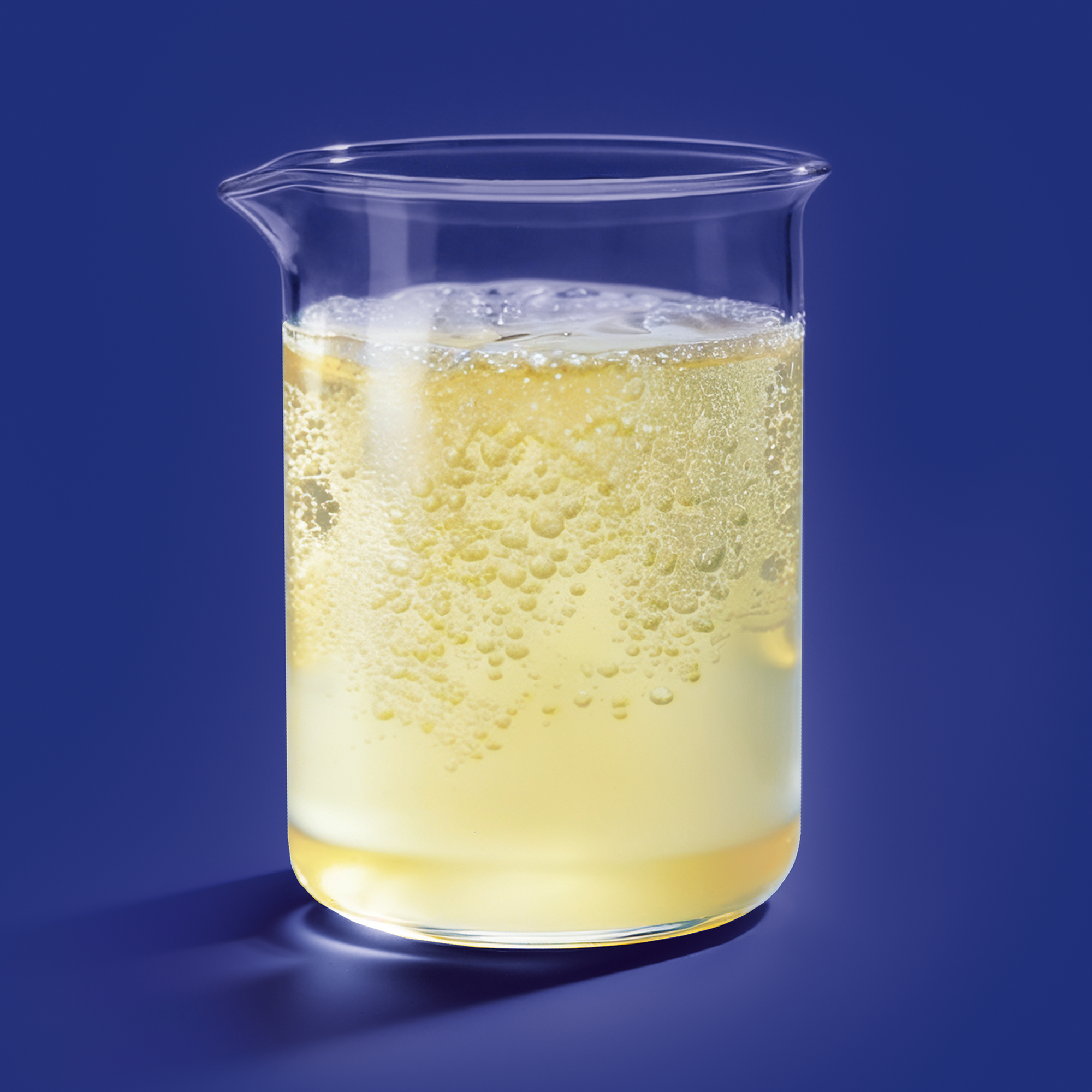 A glass filled with a pale yellow kombucha and ice cubes.