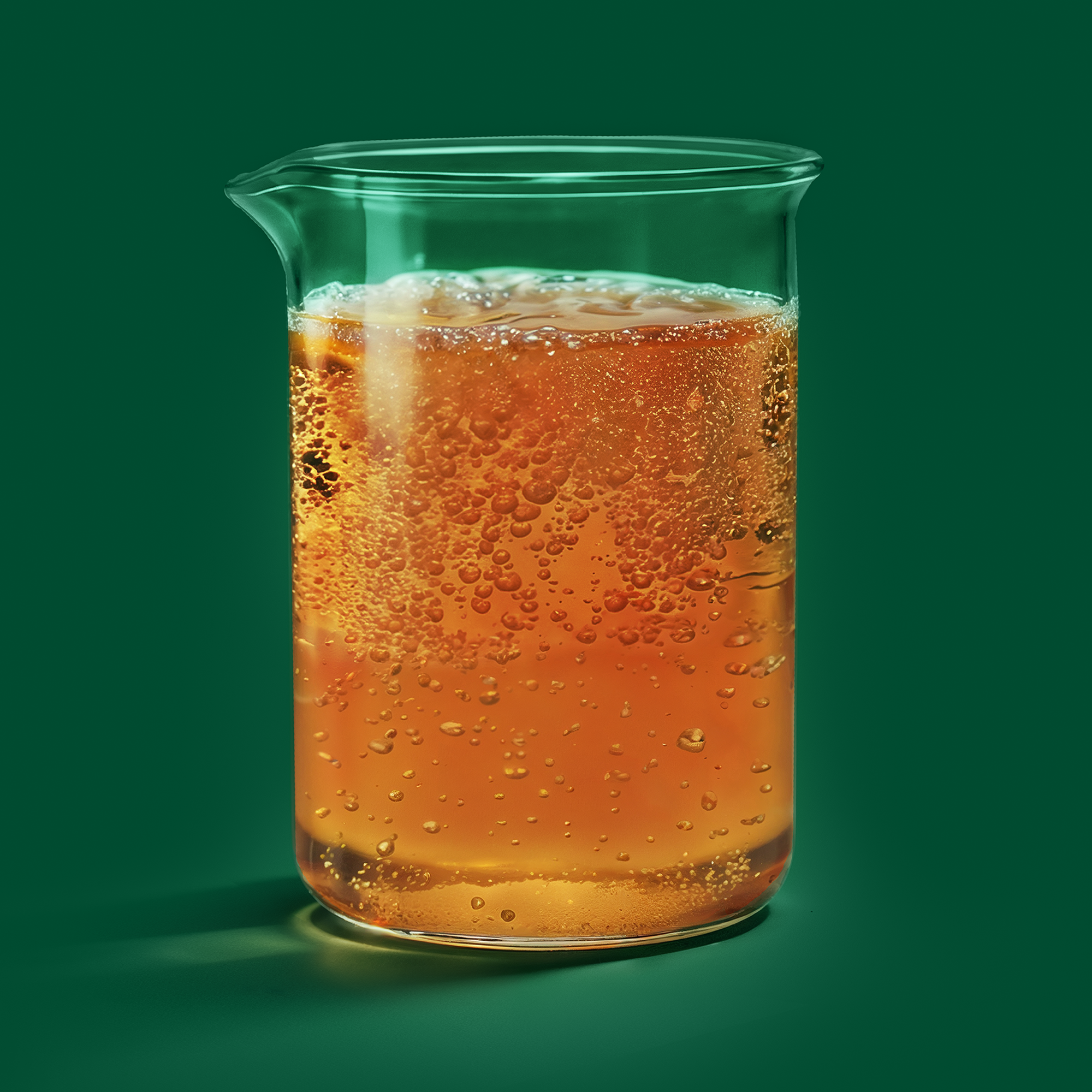 A close-up of a glass of iced orange-colored kombucha cocktail with ice cubes.