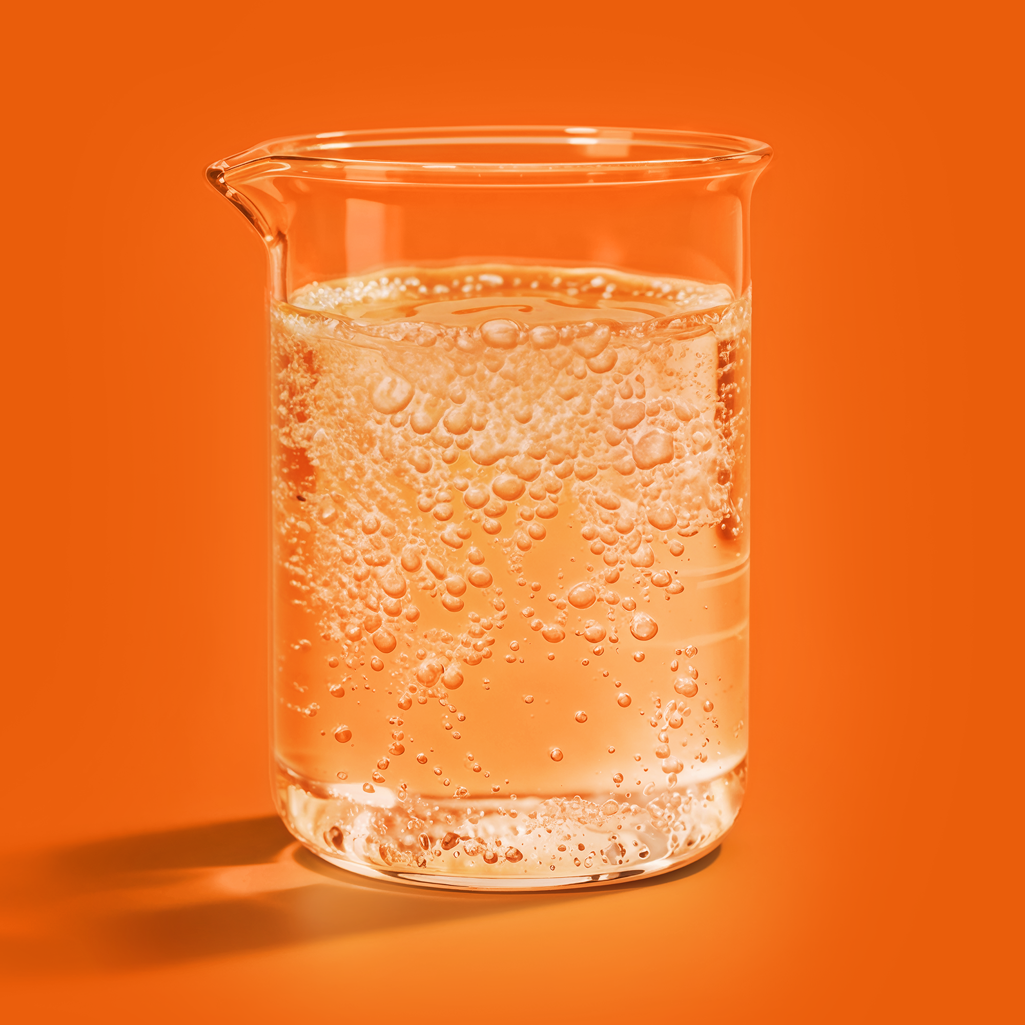 A glass of clear kombucha base liquid with ice cubes.