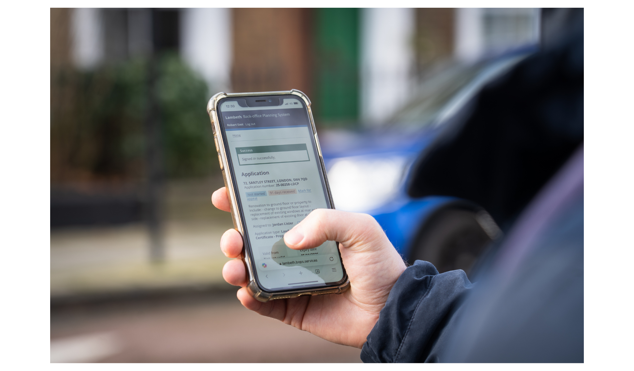 A person typing into a smartphone. The smartphone screen shows a planning application.
