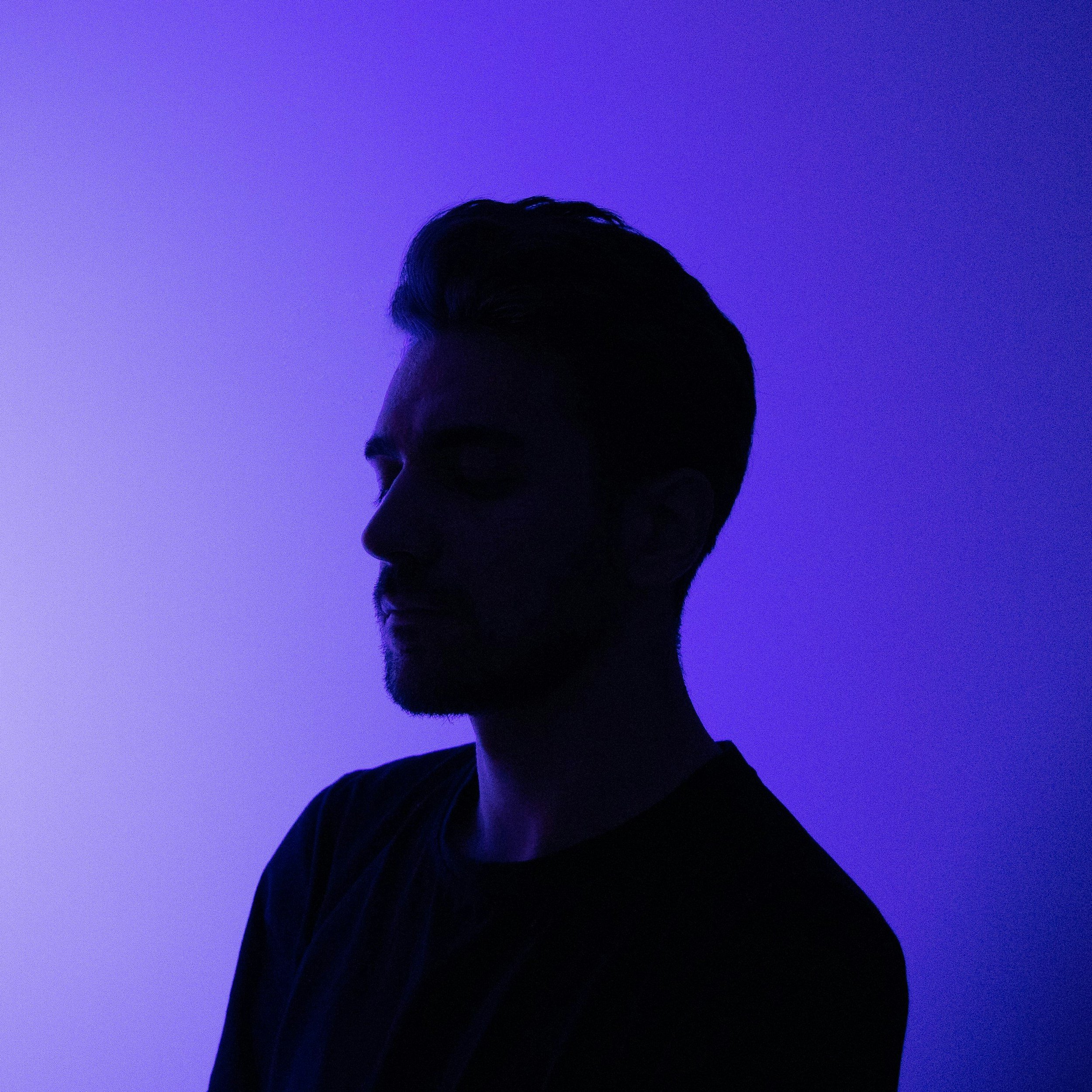 Silhouette of a man with styled hair against a purple gradient background.