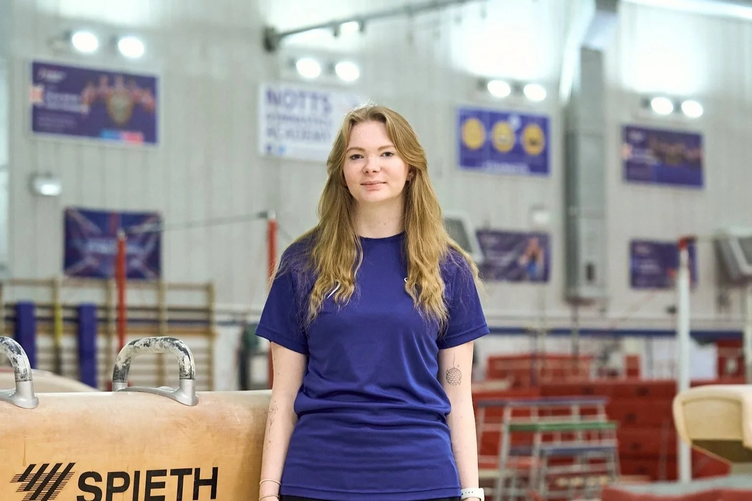 Close-up of a young girl with red hair and freckles, wearing a blue shirt, smiling slightly.