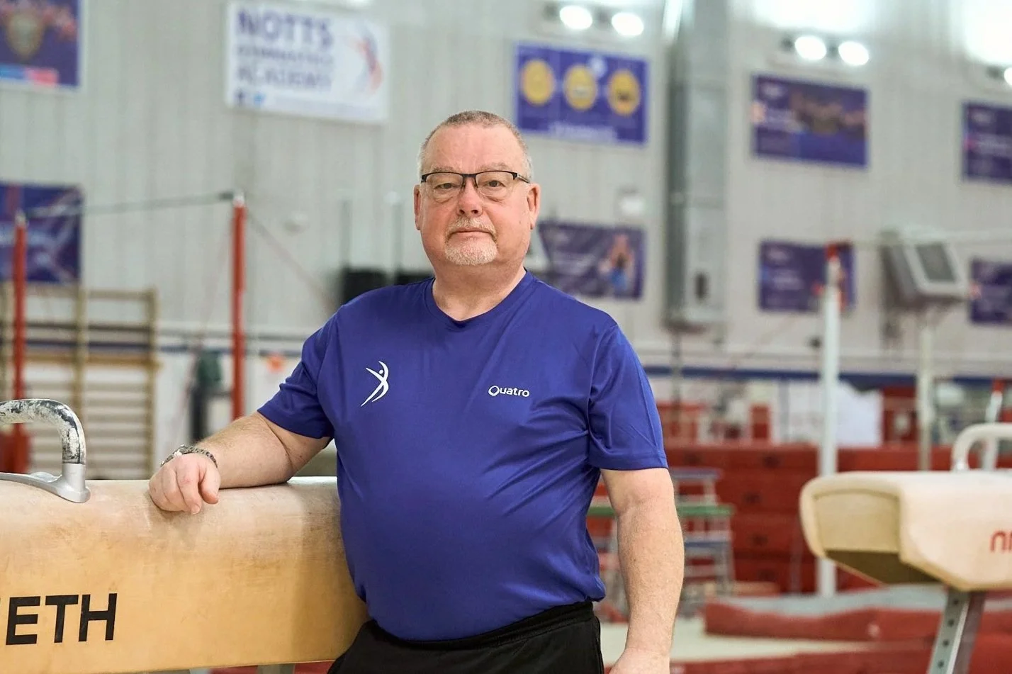Silhouette of a man with styled hair, facing left, against a purple and blue gradient background.
