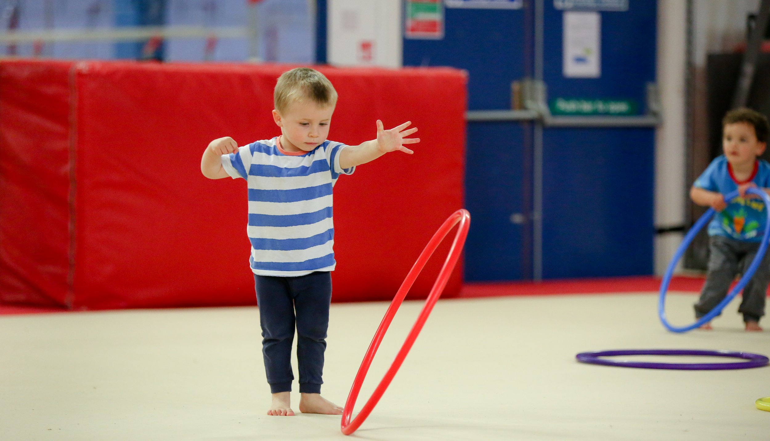 Two gymnasts gripping gymnastics rings with their hands covered in chalk, suspended in the air.