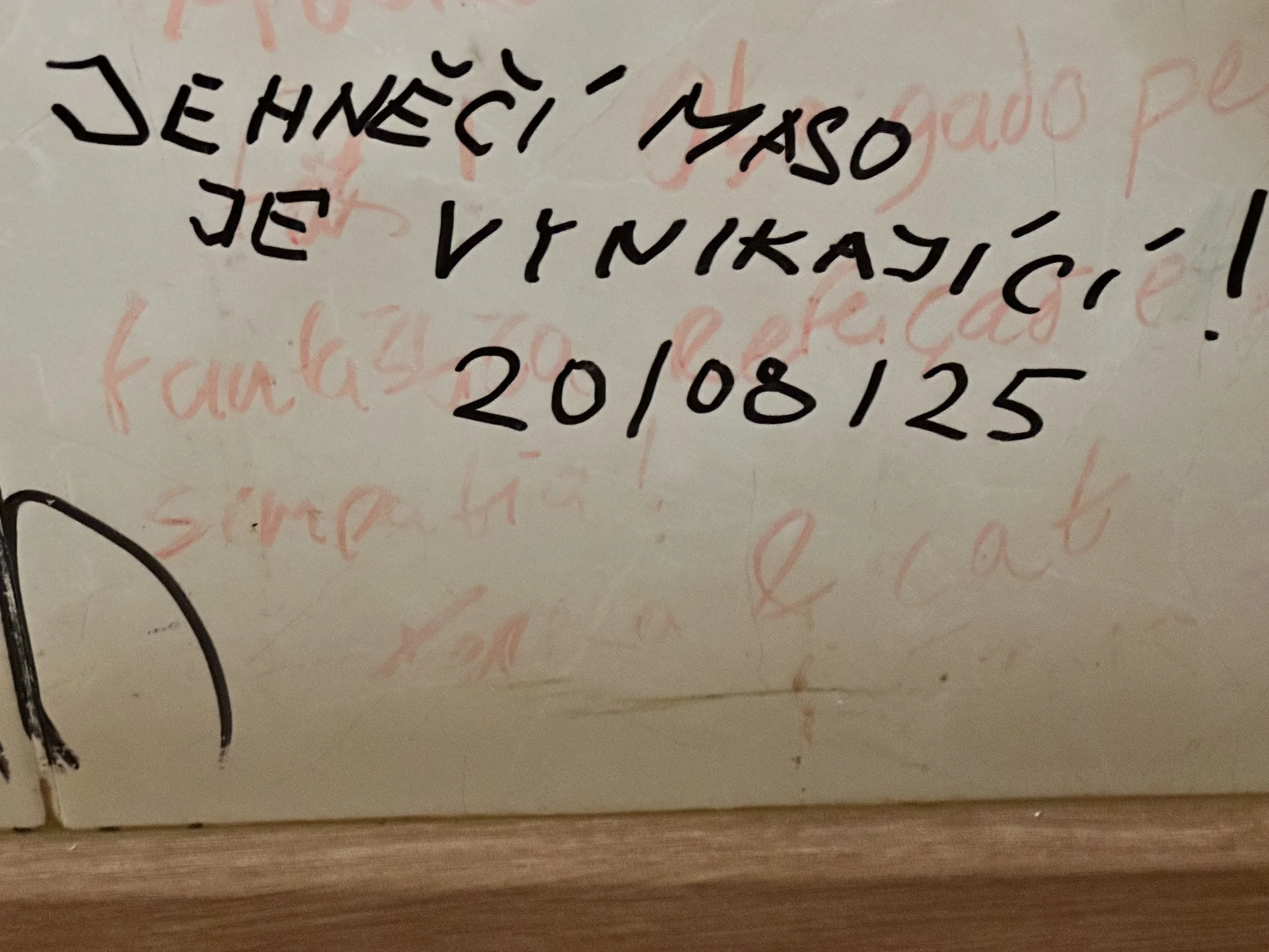 Whiteboard with handwritten message in black ink, partially crossed out in red ink, with a date 20/08/125.