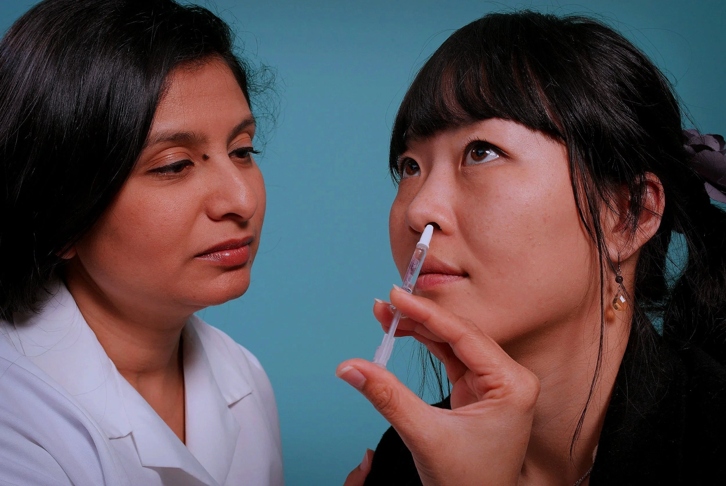 A healthcare worker administering a nasal spray vaccine to a woman.