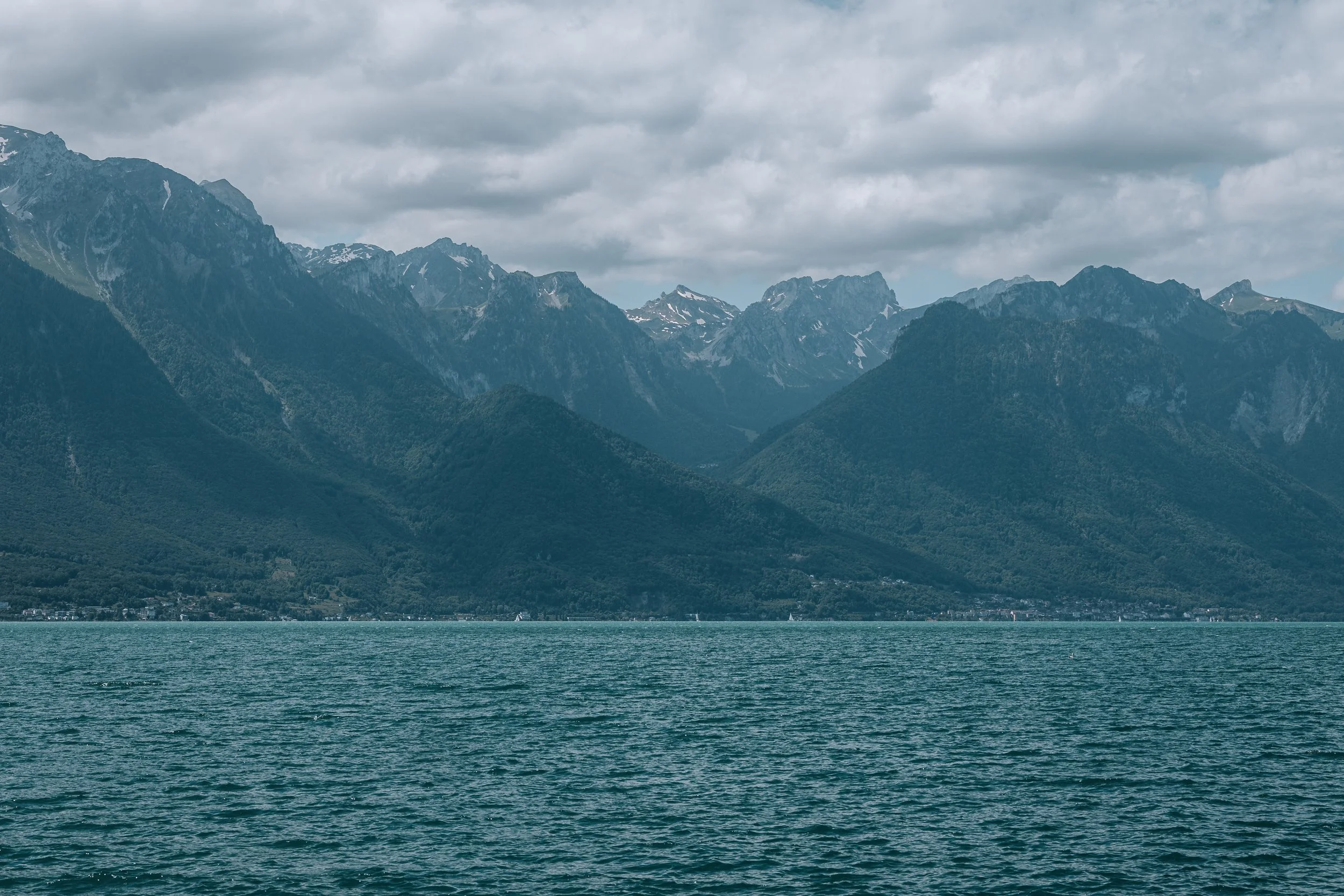 A large body of water with mountainous terrain in the background, cloudy sky overhead.