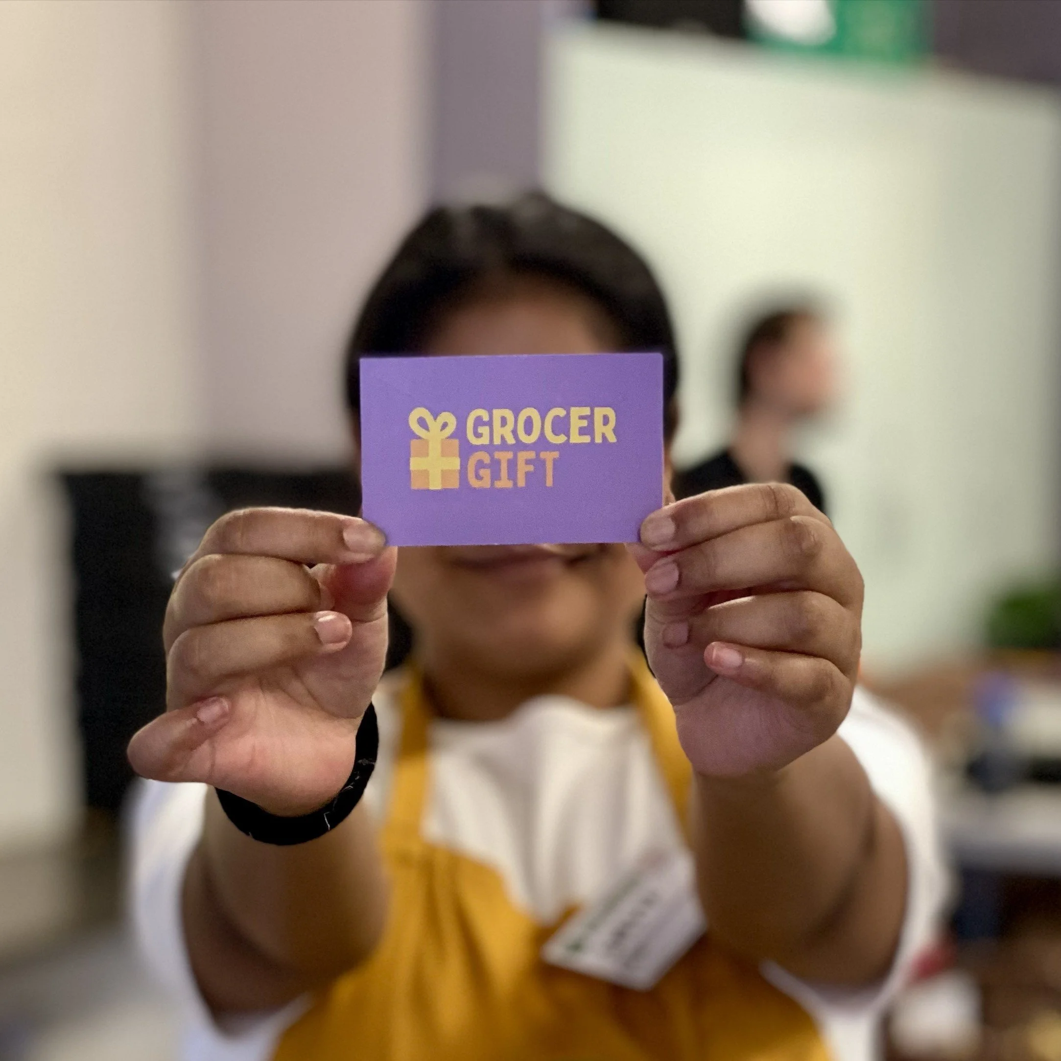 Person holding up a Grocer Gift card
