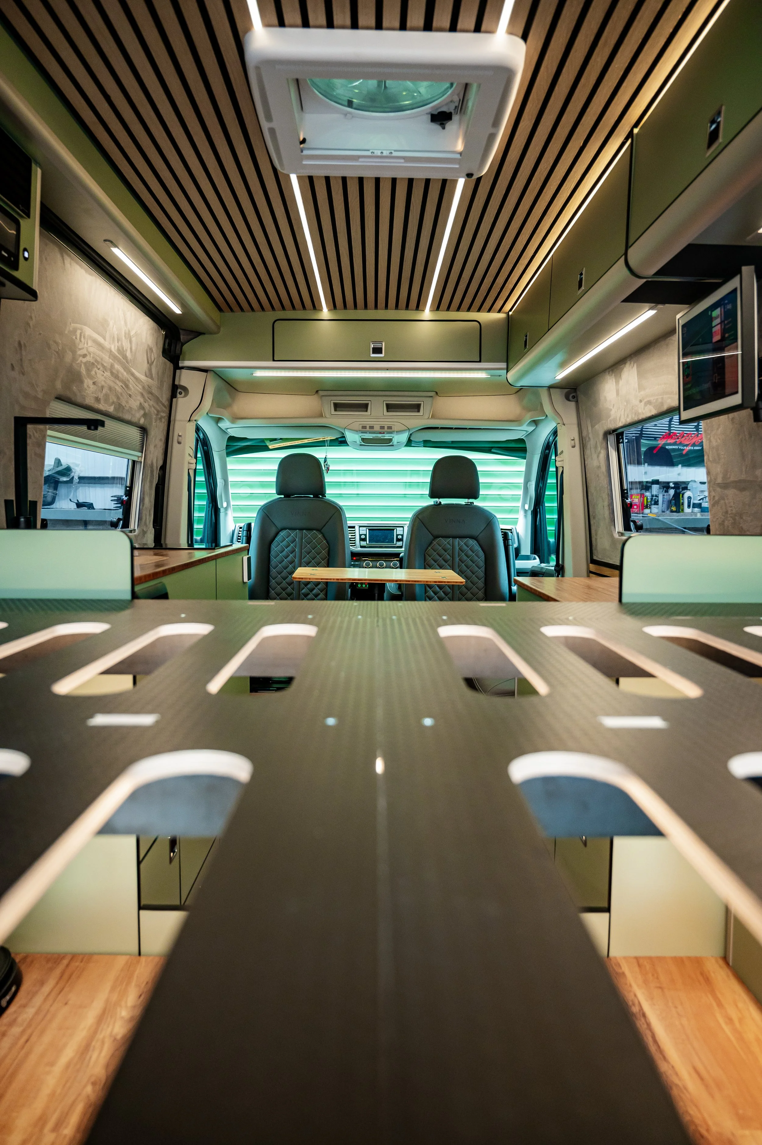 Interior of a converted van with a table, LED lighting, and a view of the front seats and dashboard.