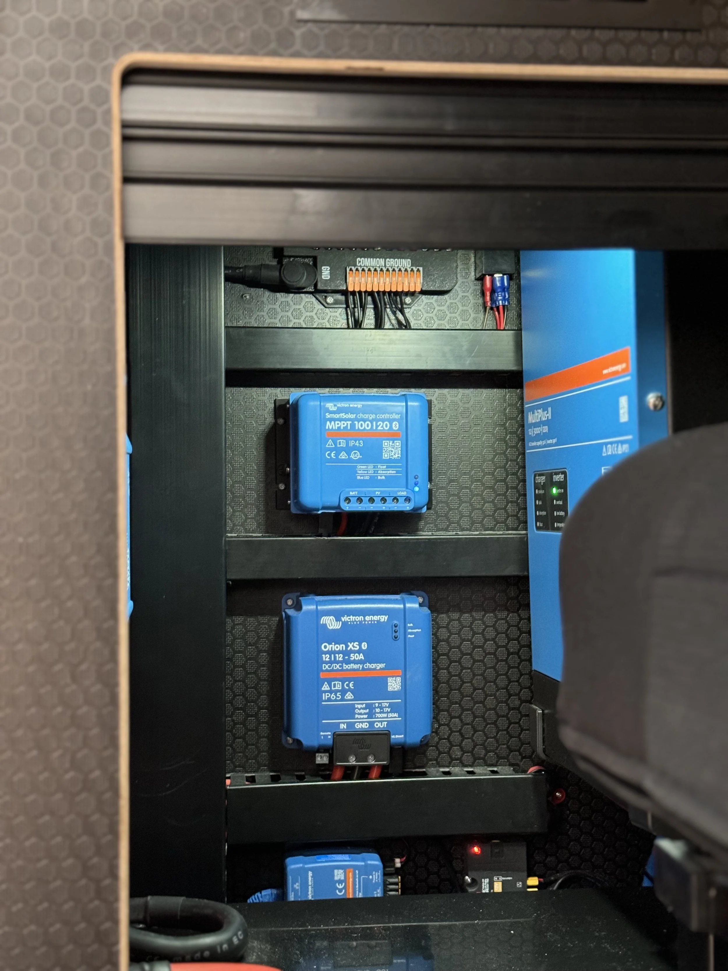 Electrical components including blue battery chargers and controllers inside a cabinet.