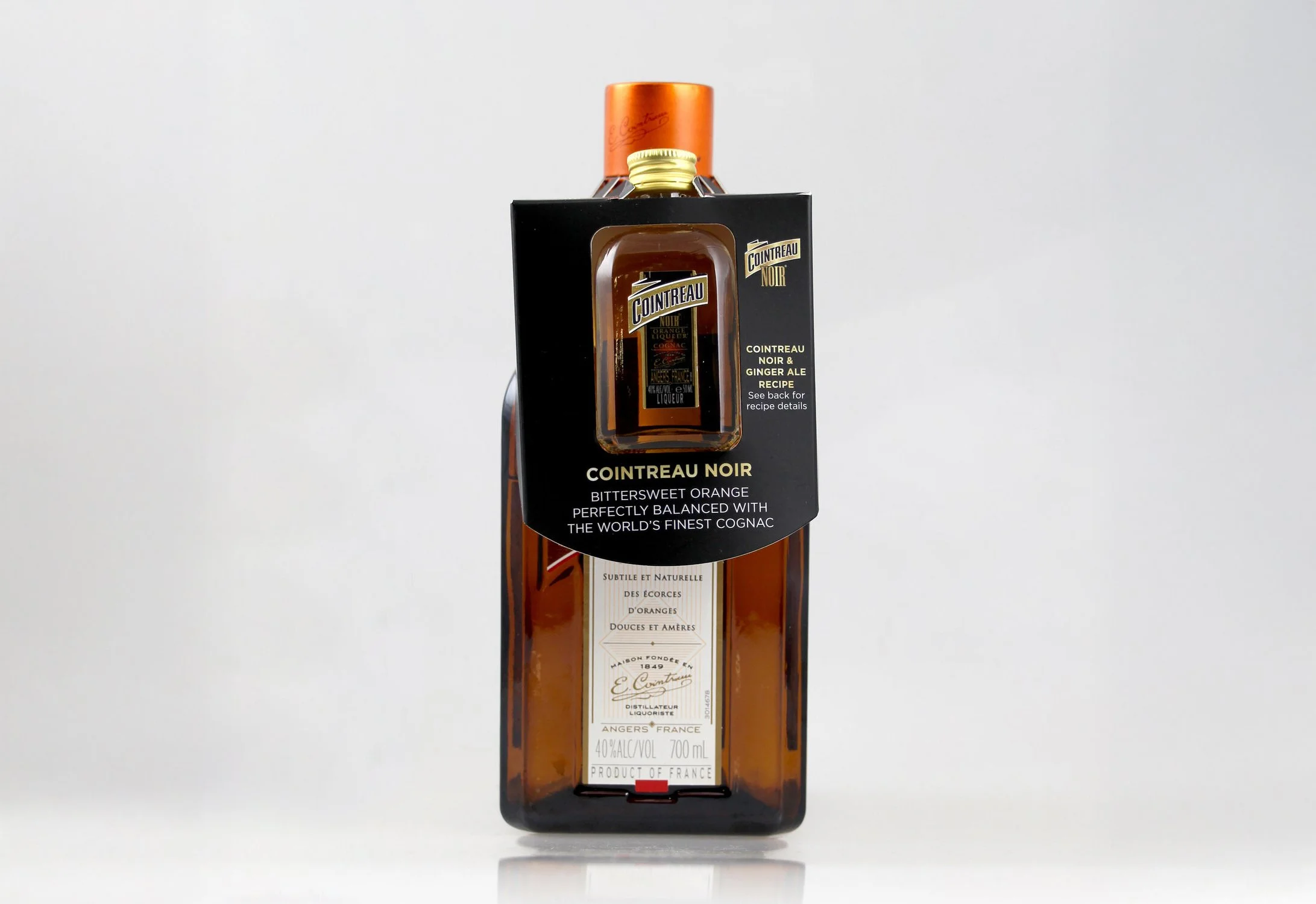 A bottle of Cointreau Noir liqueur with black and orange packaging, featuring a label indicating it's a blend of bittersweet orange and cognac, and a gold cap.