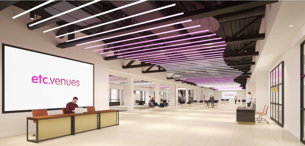 Modern lobby area with large screen displaying "etc.venues," featuring a reception desk, open seating, and purple ceiling lights.