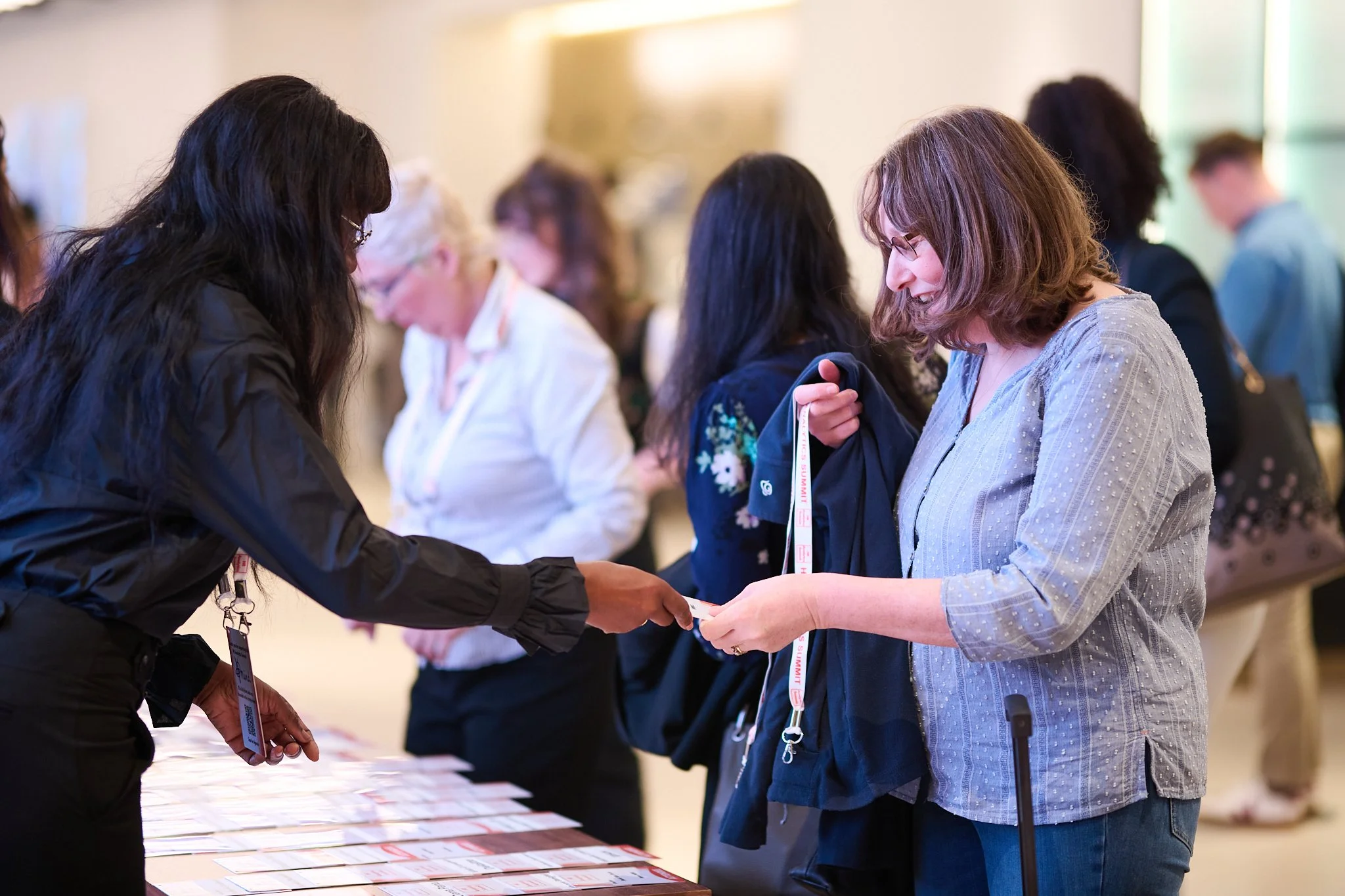 People at a conference registration desk exchanging badges.