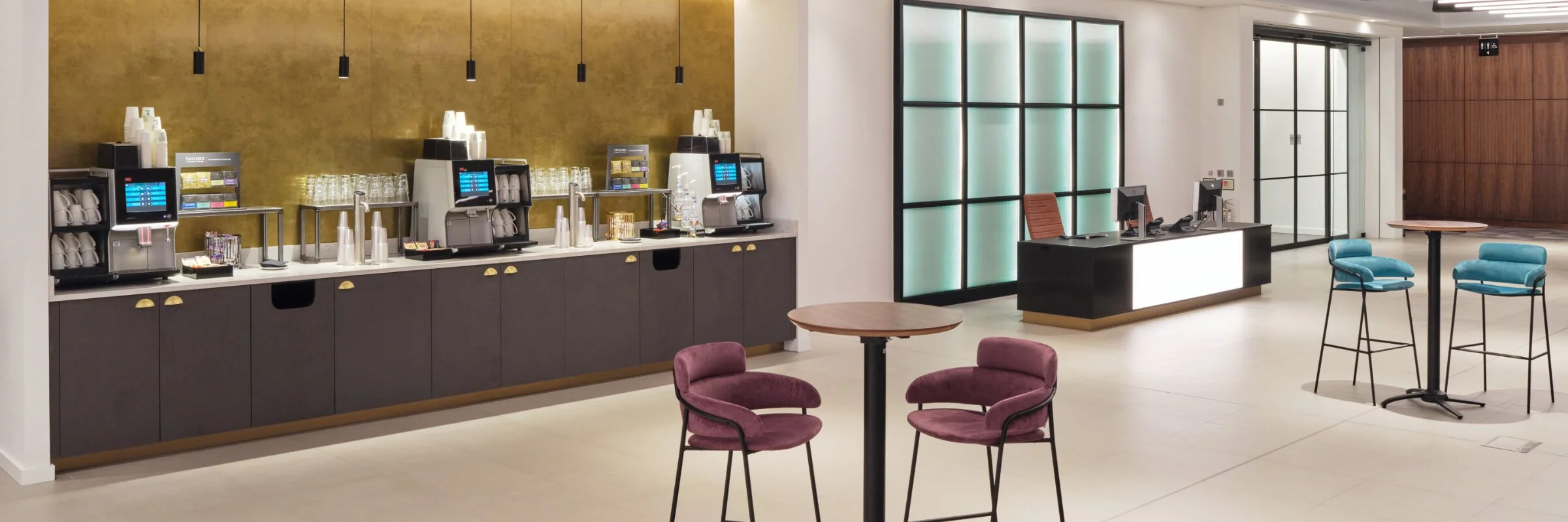 Modern café area with a coffee station, tables, and colorful chairs