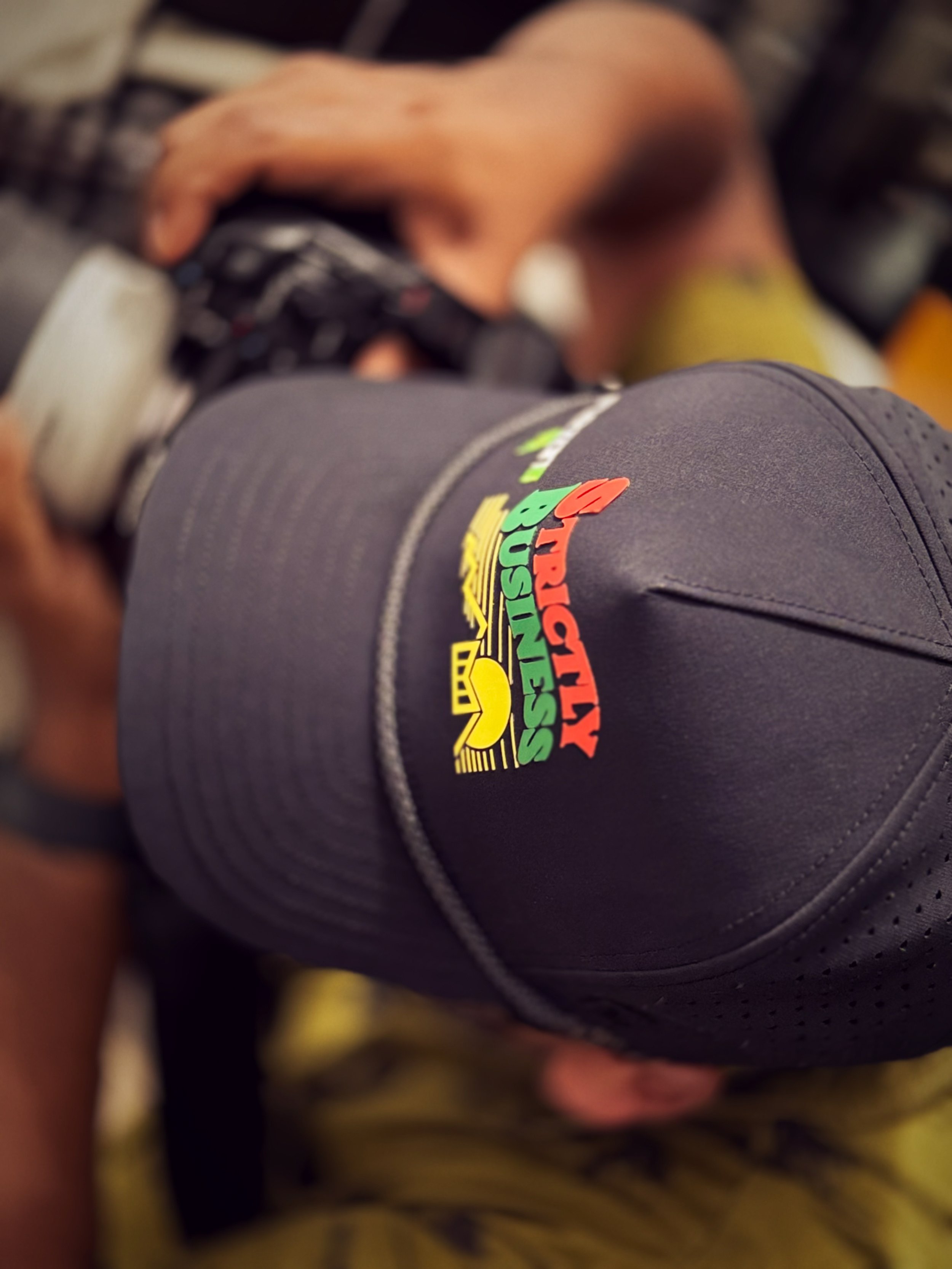 A person wearing a black cap with a colorful logo that reads 'Lucky Busters'.