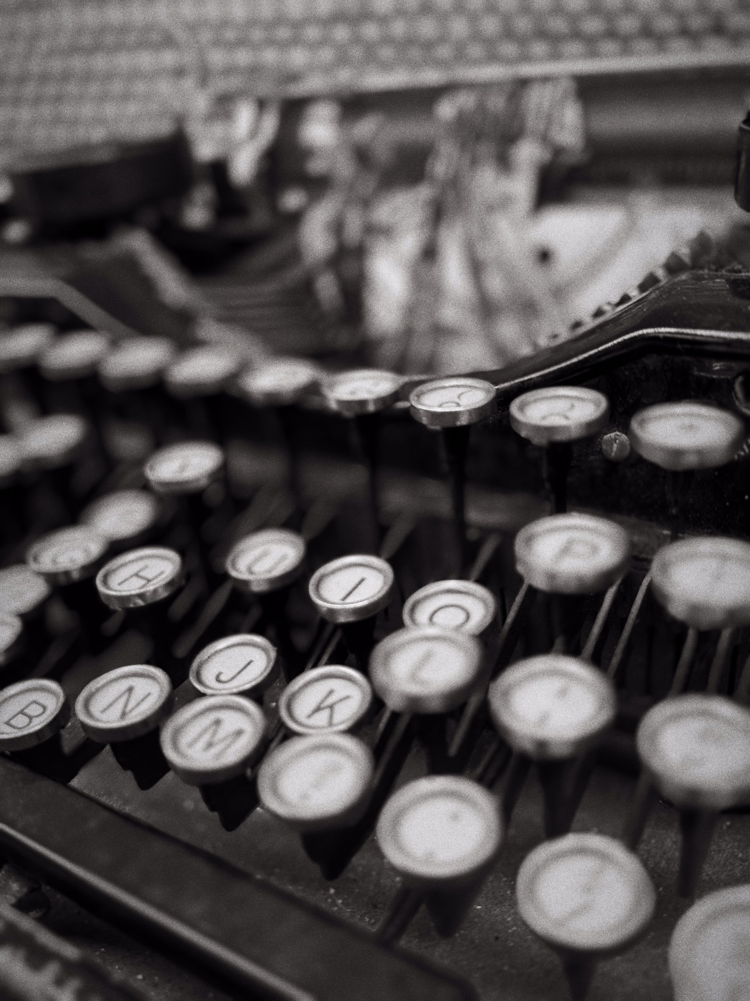 Close-up of an old typewriter with round keys showing letters and numbers, in black and white.