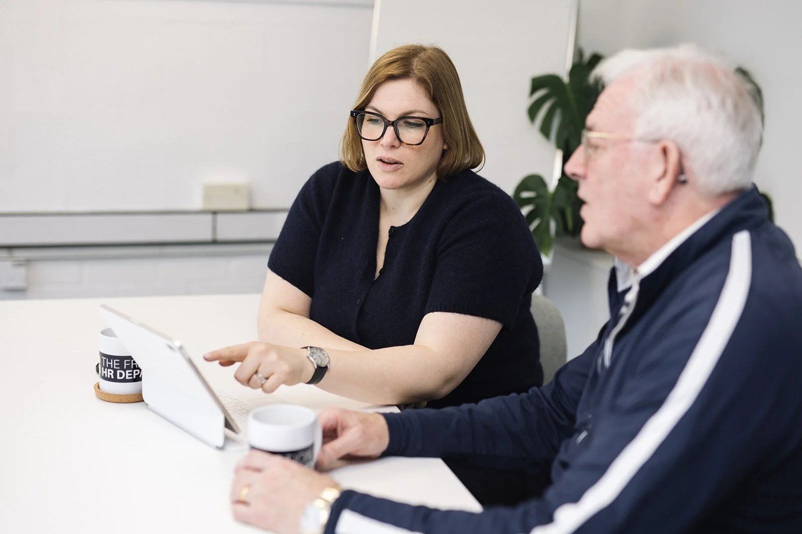 Sarah Ropek discussing information on a tablet with a client during a business meeting