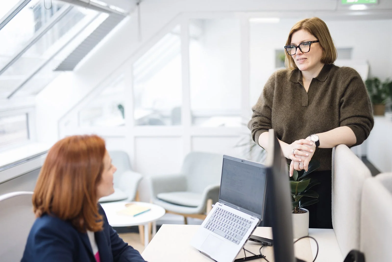HR consultant speaking with a colleague across an office workspace during a business discussion.