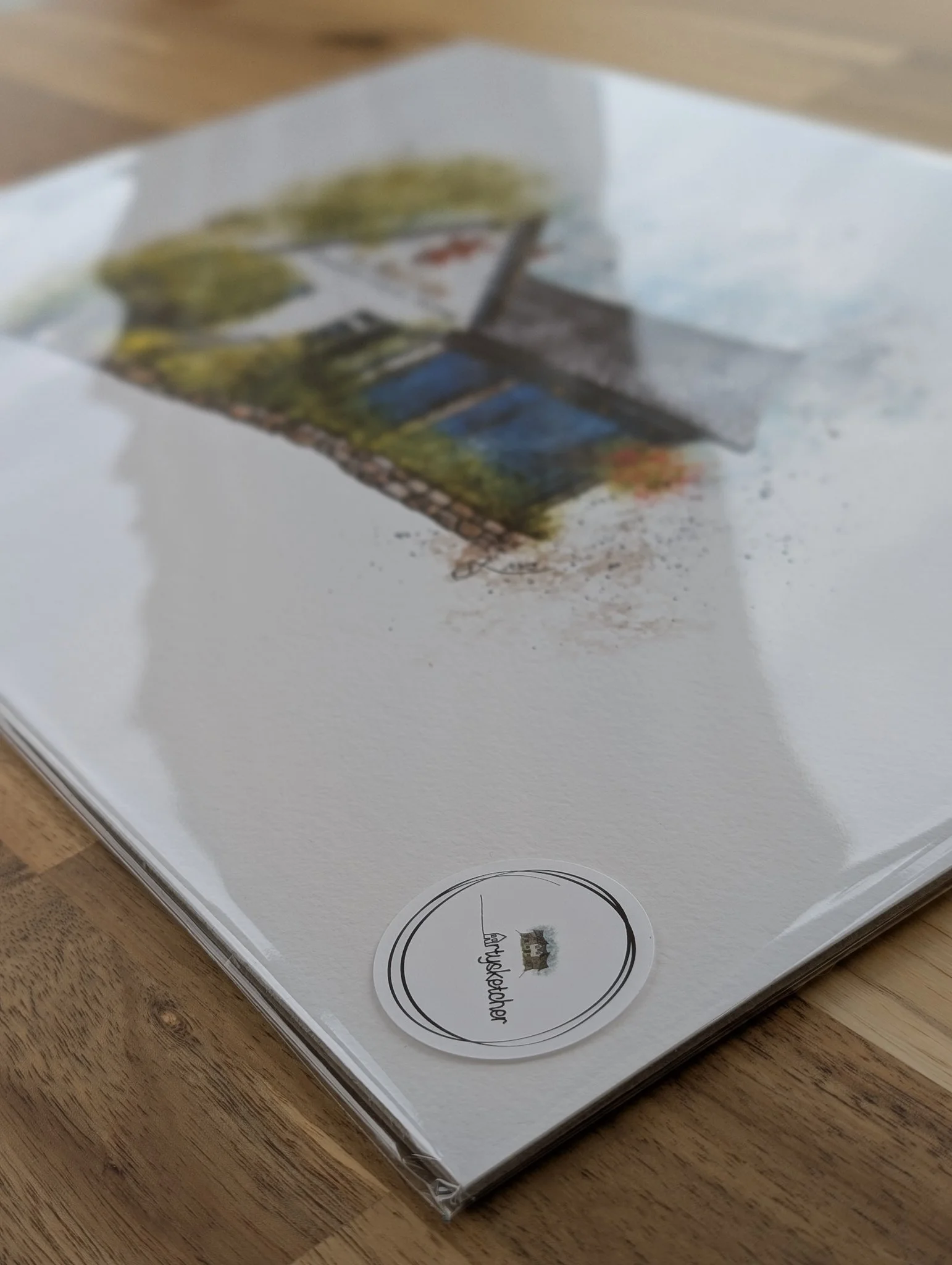 A printed photograph inside a clear plastic sleeve, lying on a wooden surface, with a round label at the bottom.