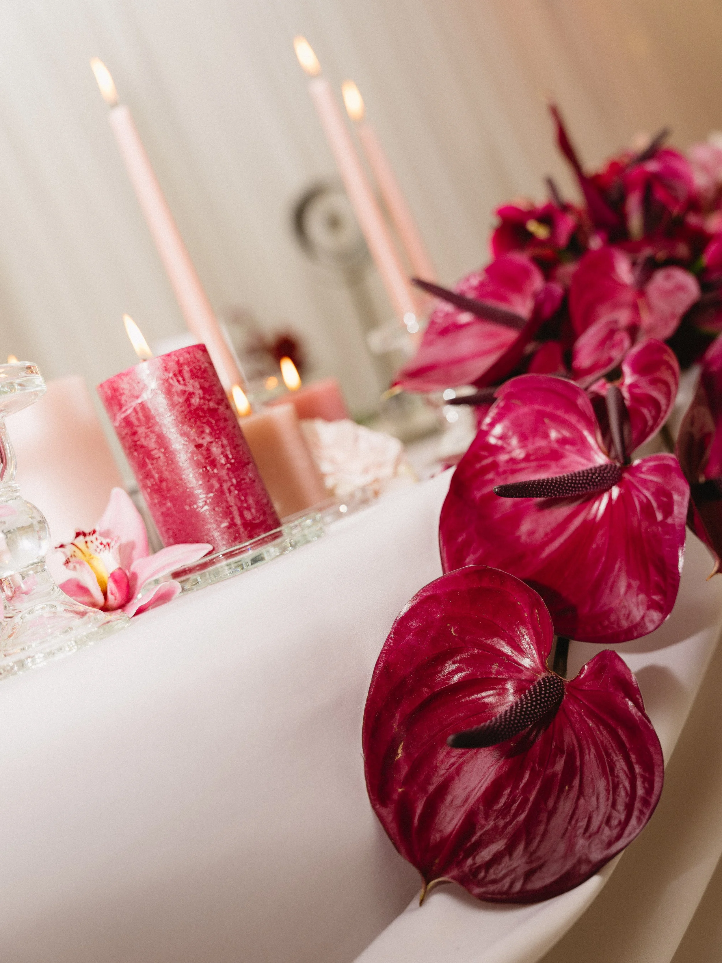 Pink and red floral centerpiece with pink candles on a table.