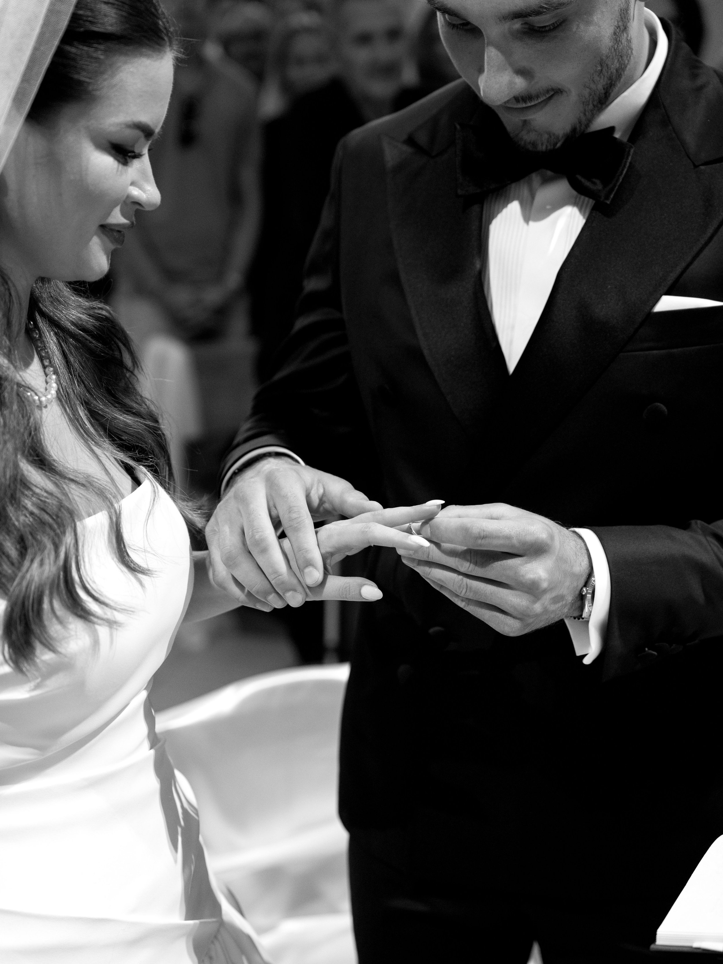 A black and white photo of a wedding ceremony showing a bride and groom exchanging rings.