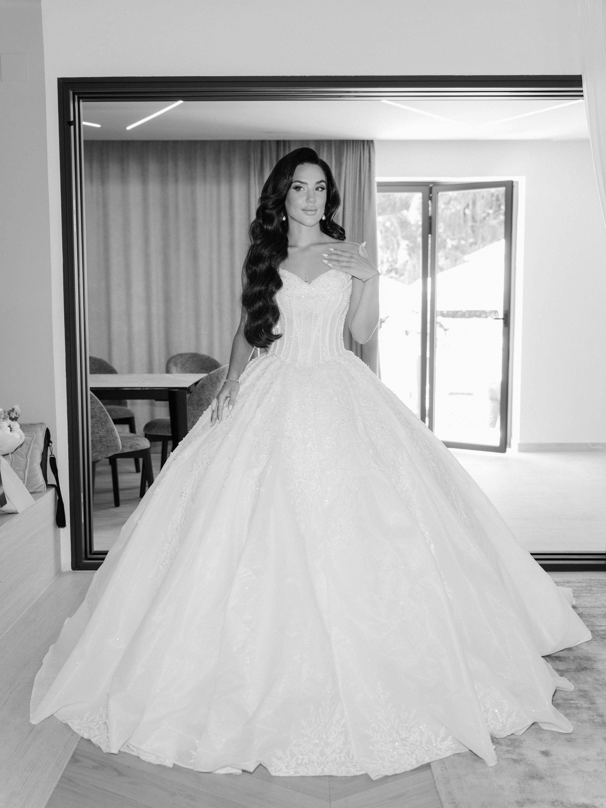 A woman in a wedding dress standing in front of a large mirror.