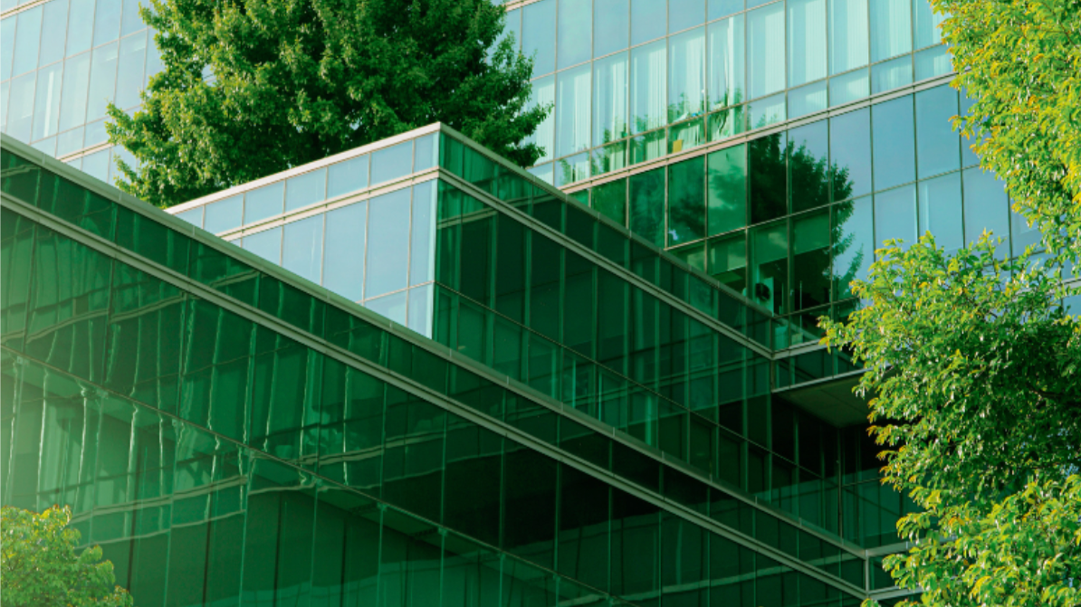 Modern building with green-tinted glass windows and surrounding trees.