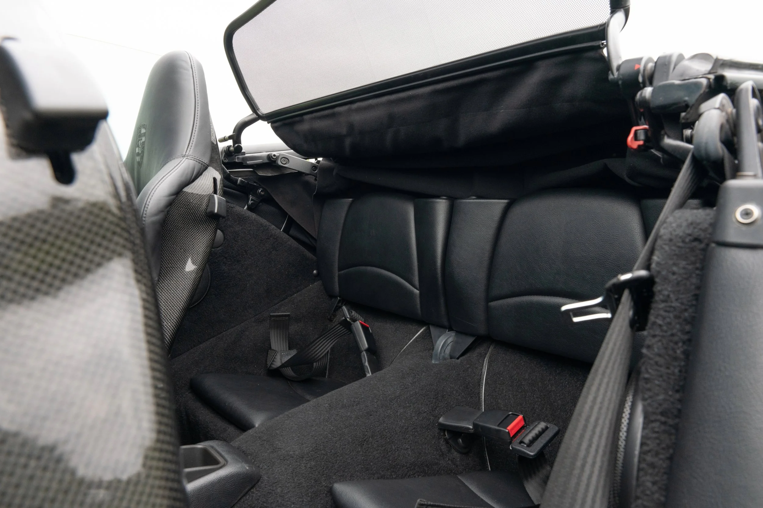 Interior of a compact vehicle with seats, seat belts, and cargo space visible in the back area.