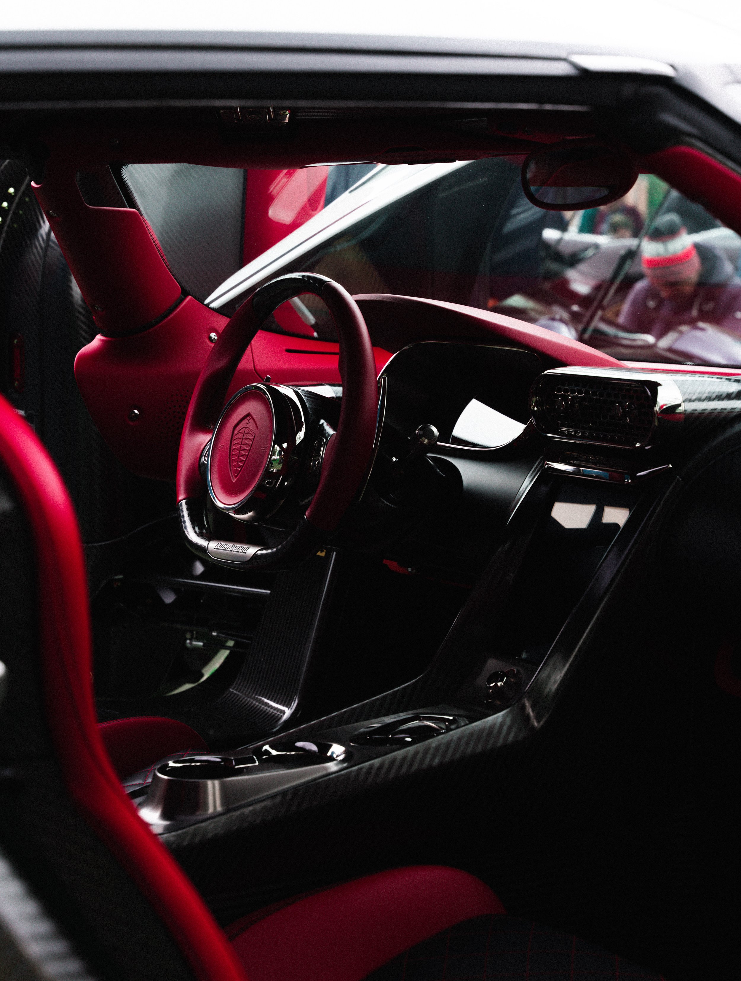 Interior of a high-performance sports car with a red and black color scheme, featuring a racing steering wheel and carbon fiber dashboard.