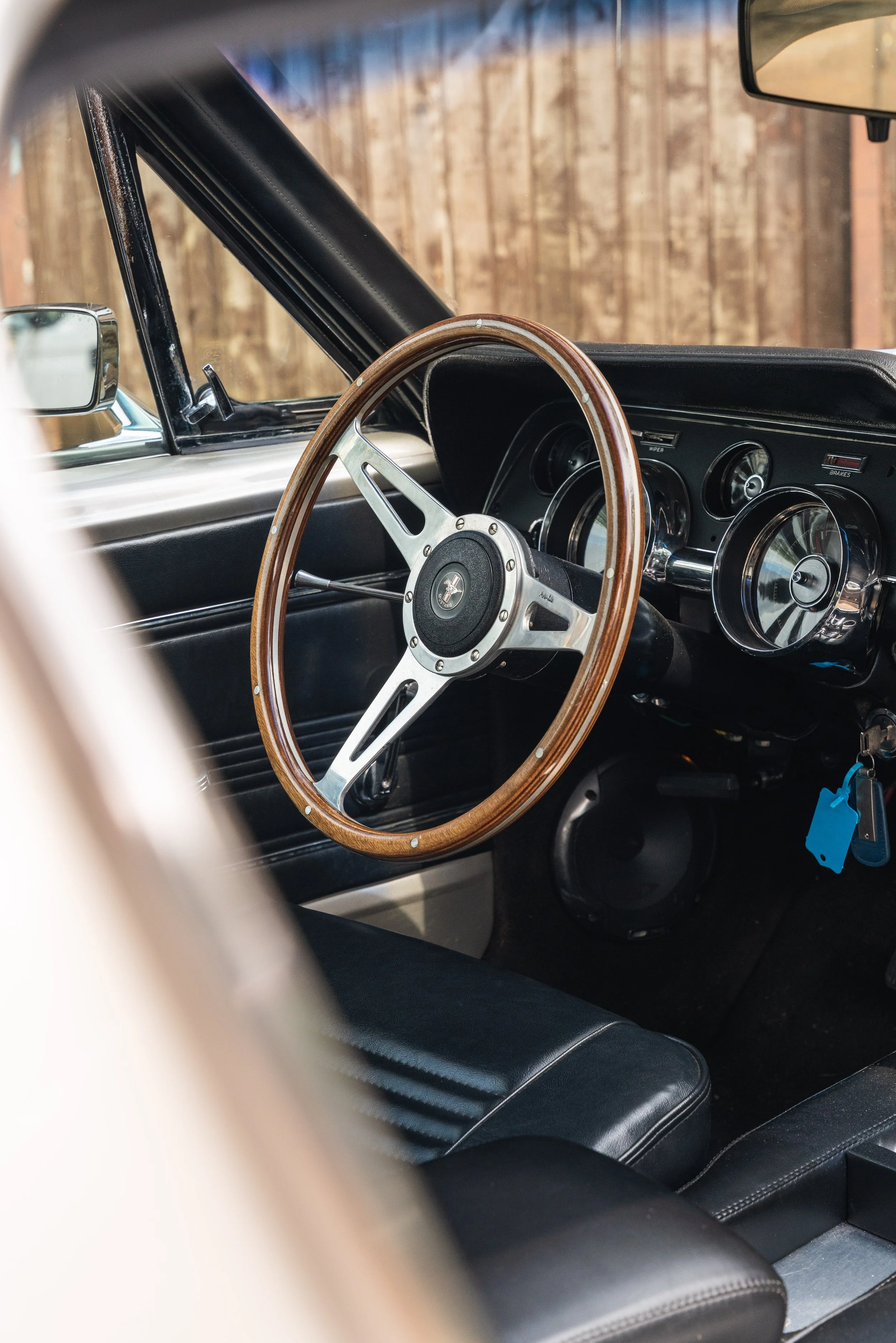 Interior of a vintage car with a wooden steering wheel and black dashboard.