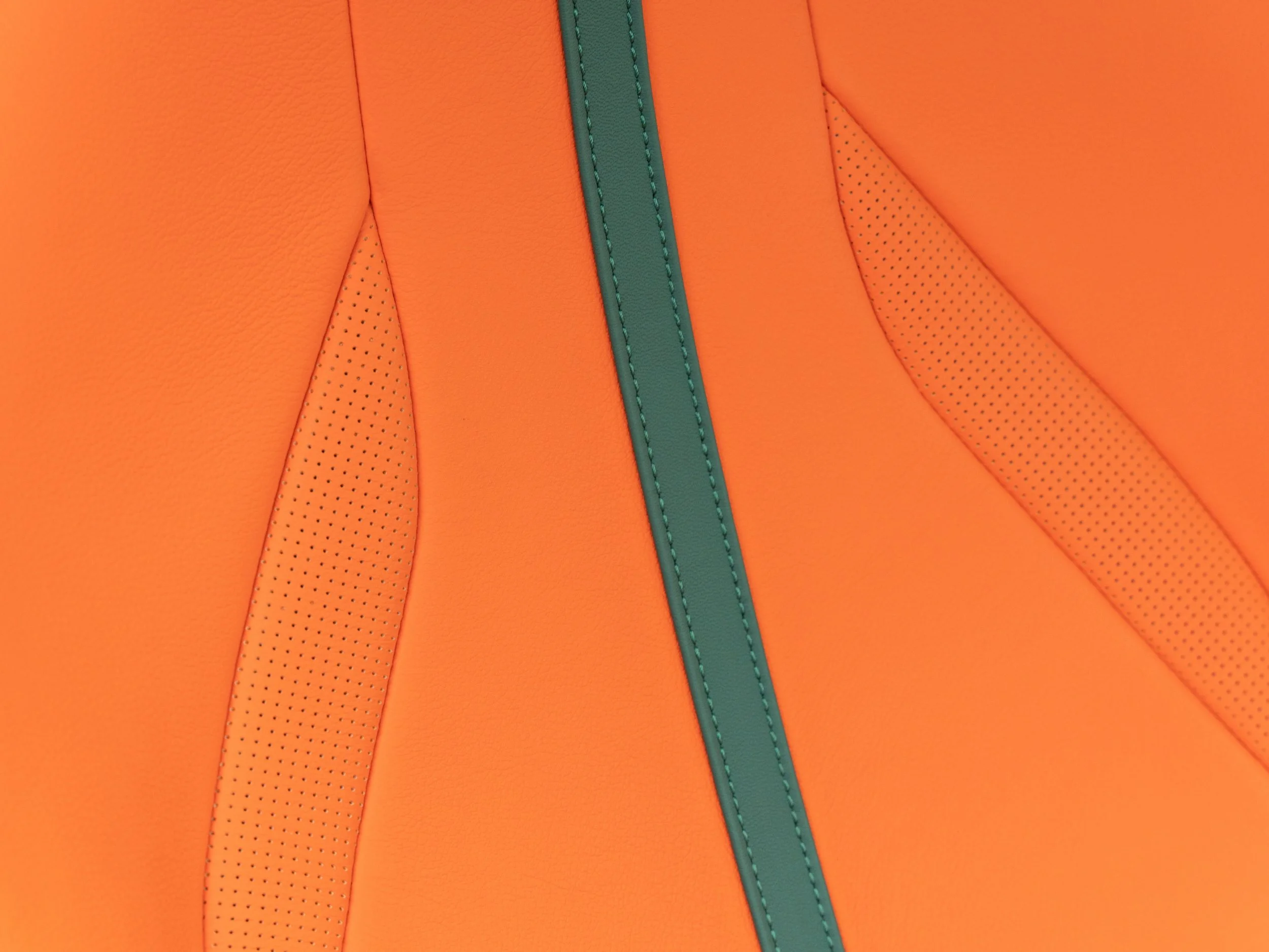 Close-up of an orange upholstered surface with turquoise trim and stitching.