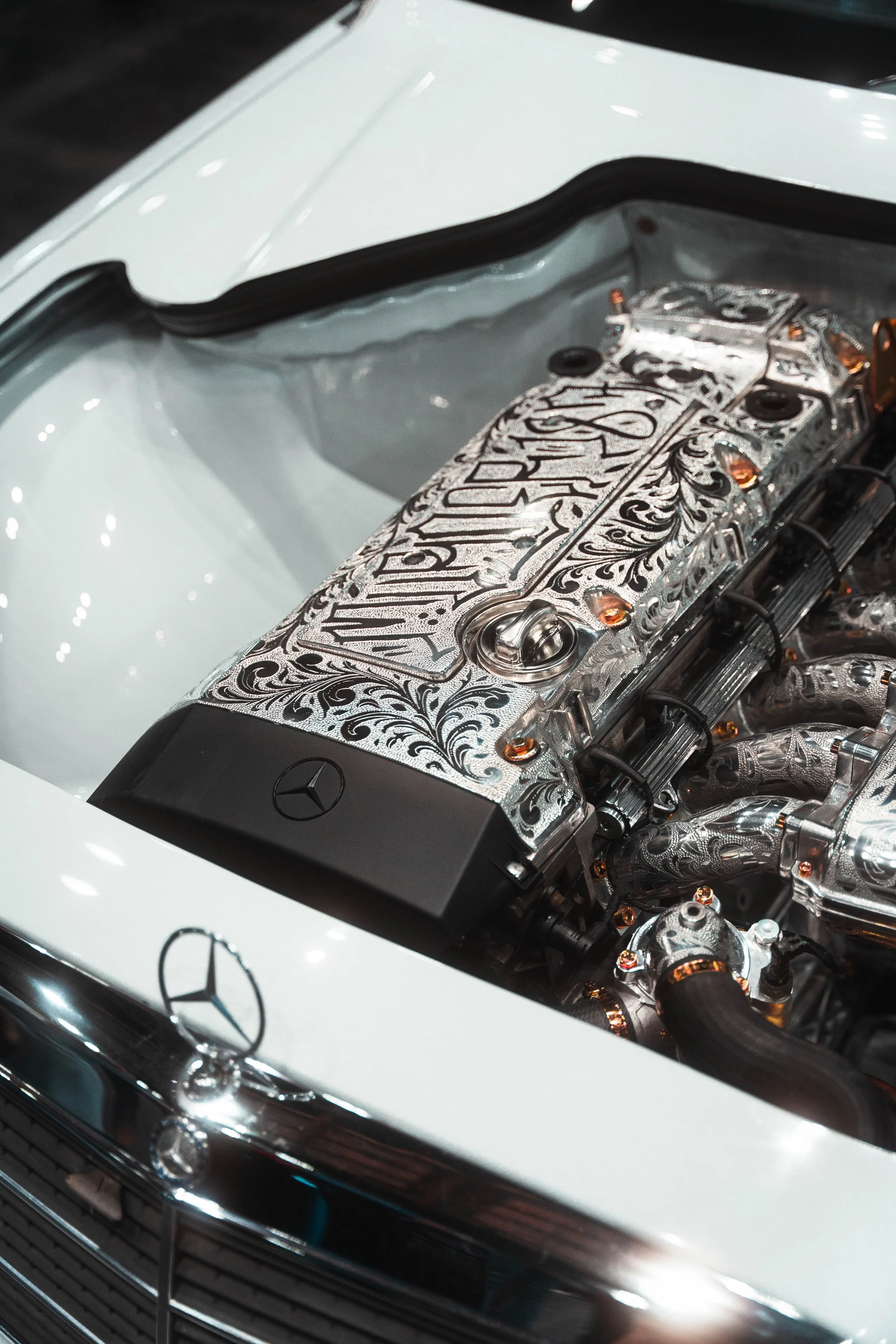 Close-up of a Mercedes engine with ornate, engraved silver detailing and the Mercedes logo on the engine cover.