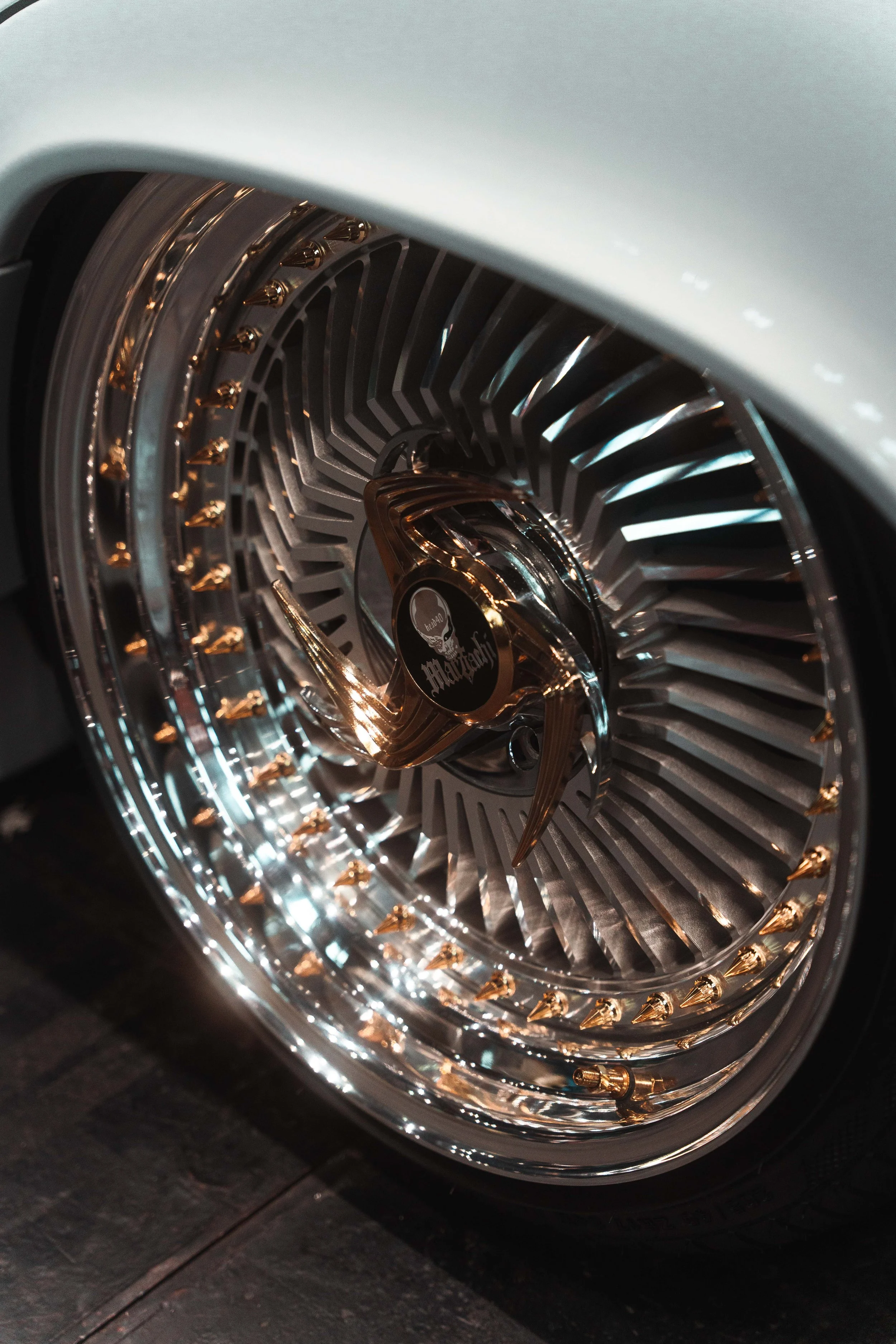Close-up of a custom chrome wheel with gold lug nuts and a Harley-Davidson logo center cap.
