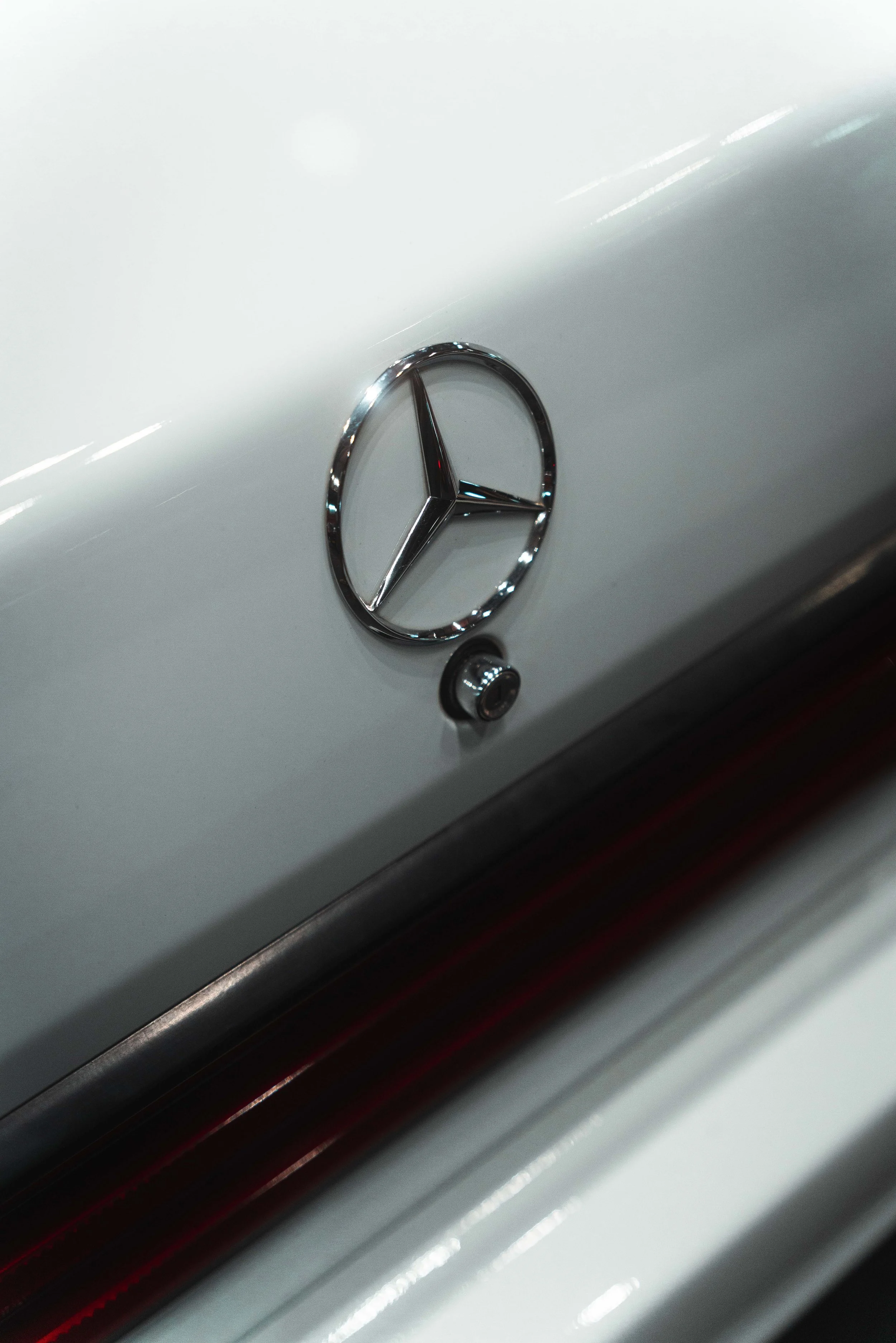 Close-up of a Mercedes-Benz emblem on a white car's rear.