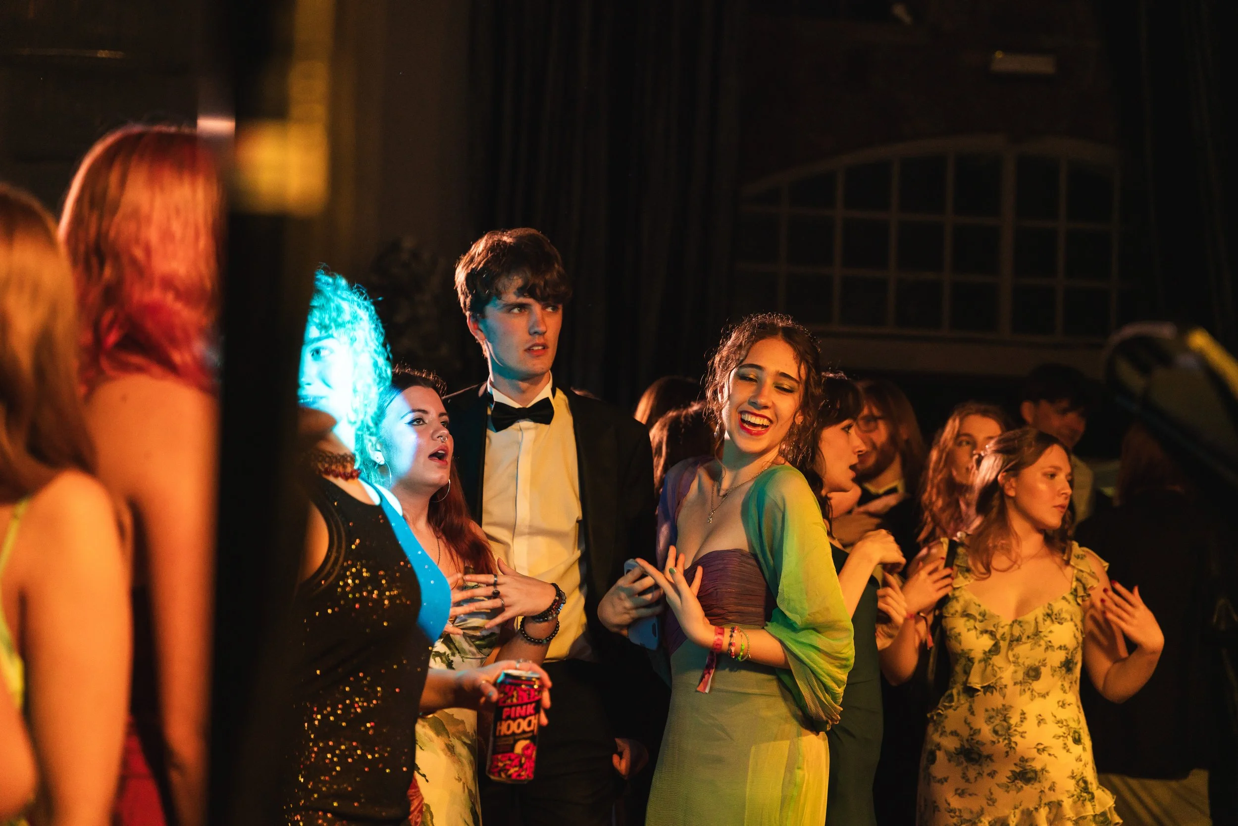 Group of young people at a party, dressed in formal and semi-formal attire, socializing and having fun.